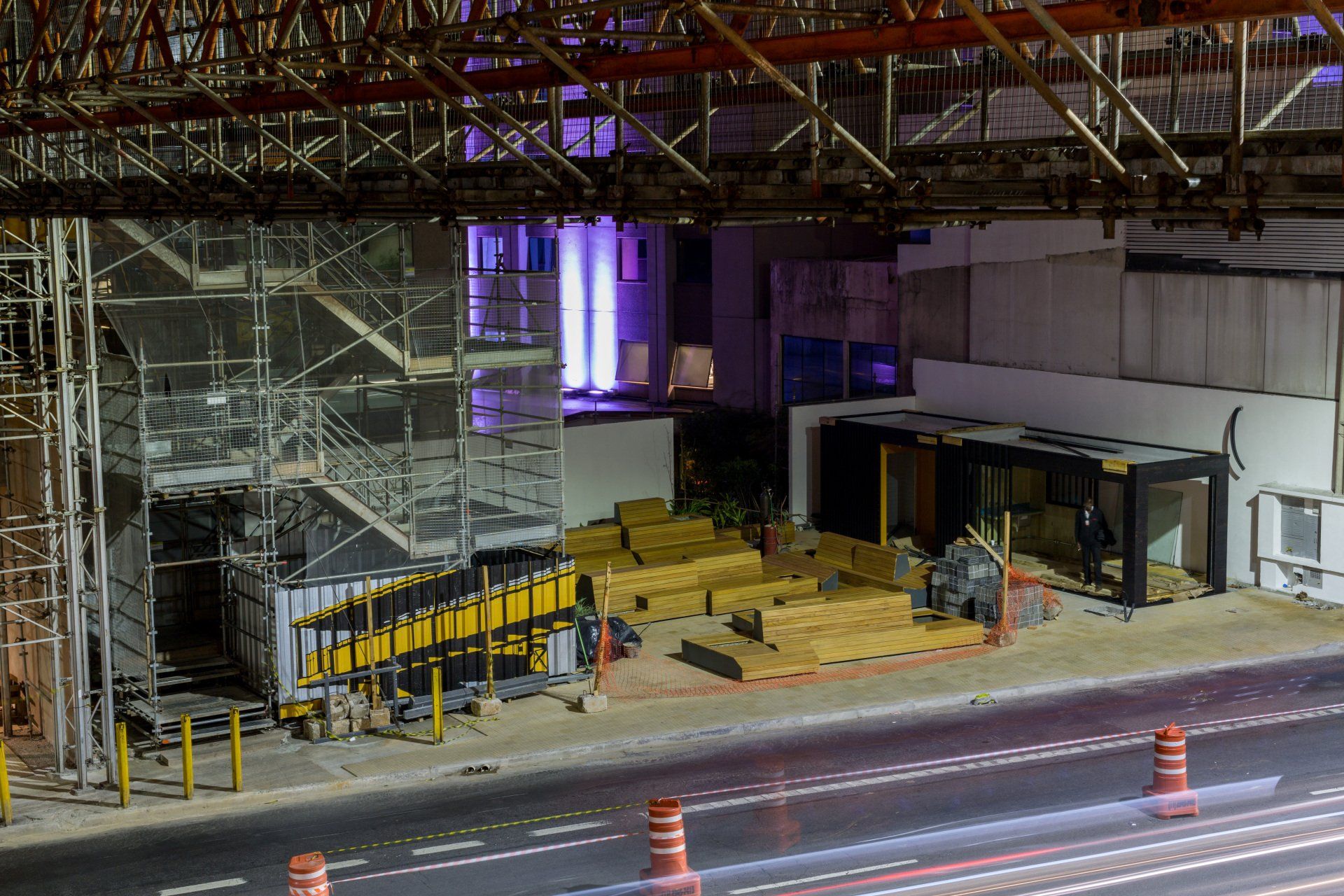 Um canteiro de obras com muitos andaimes e cones na beira da estrada.