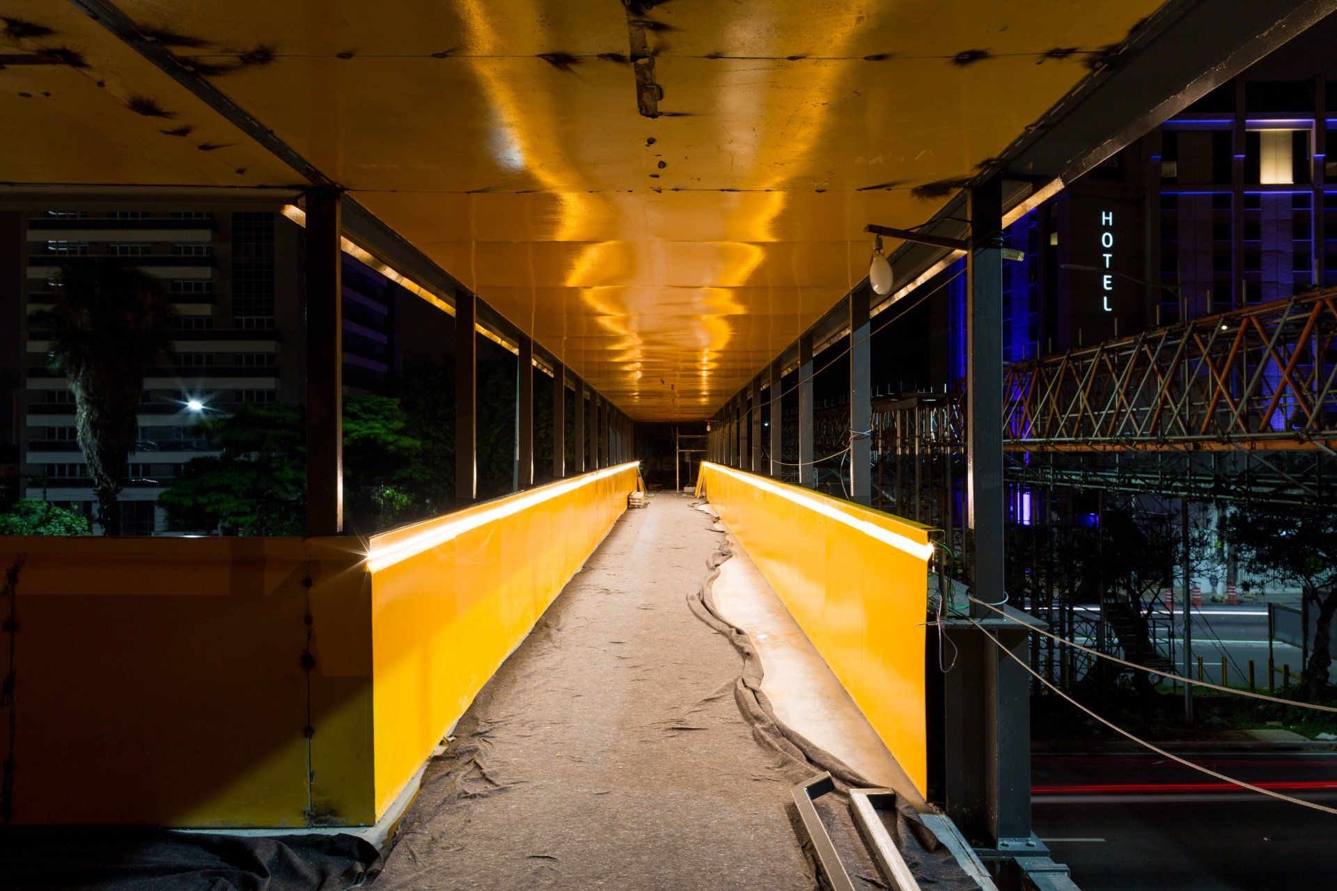 Uma passarela amarela que leva a uma ponte à noite