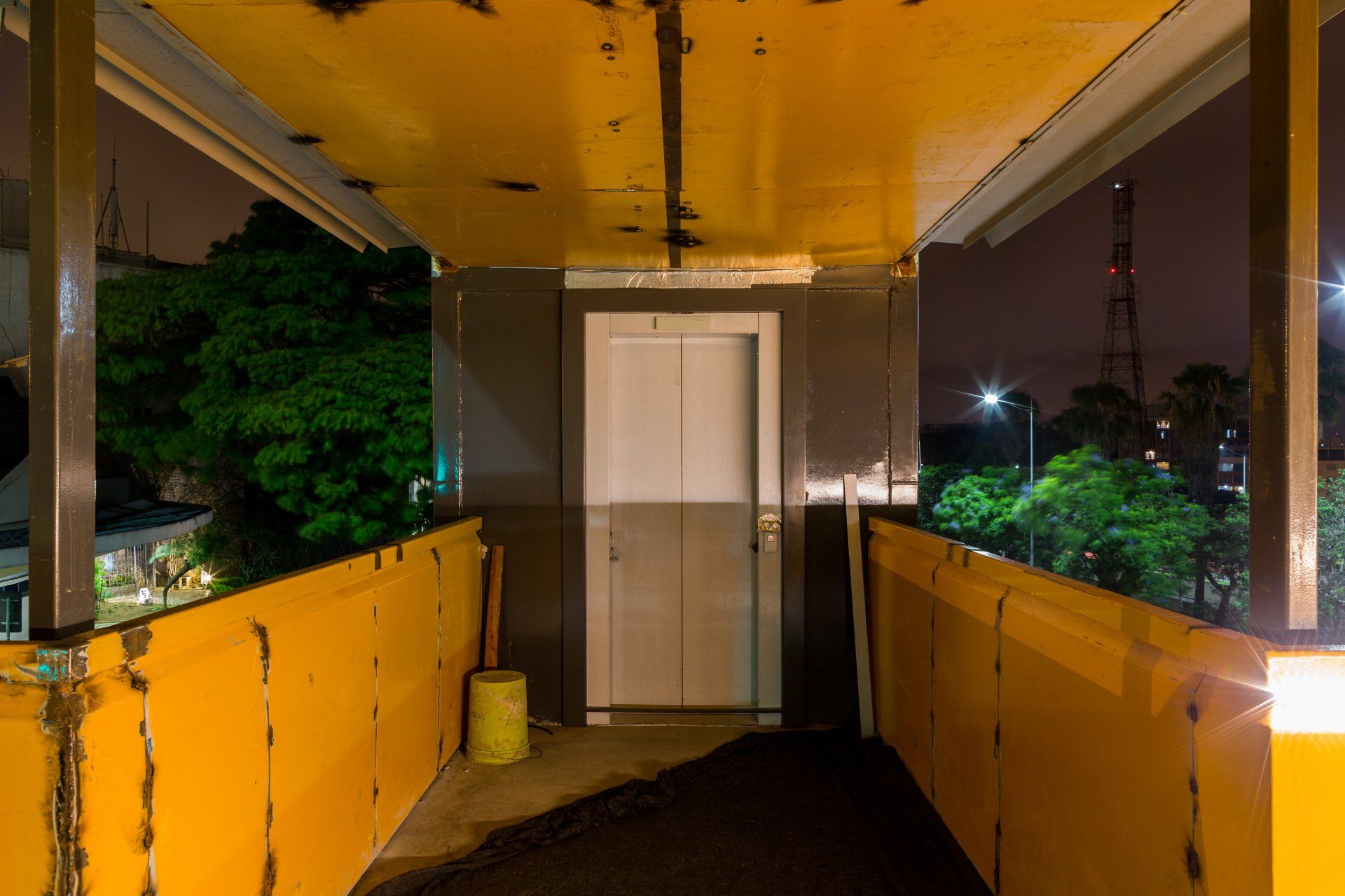 Uma passarela amarela que leva a um elevador à noite.
