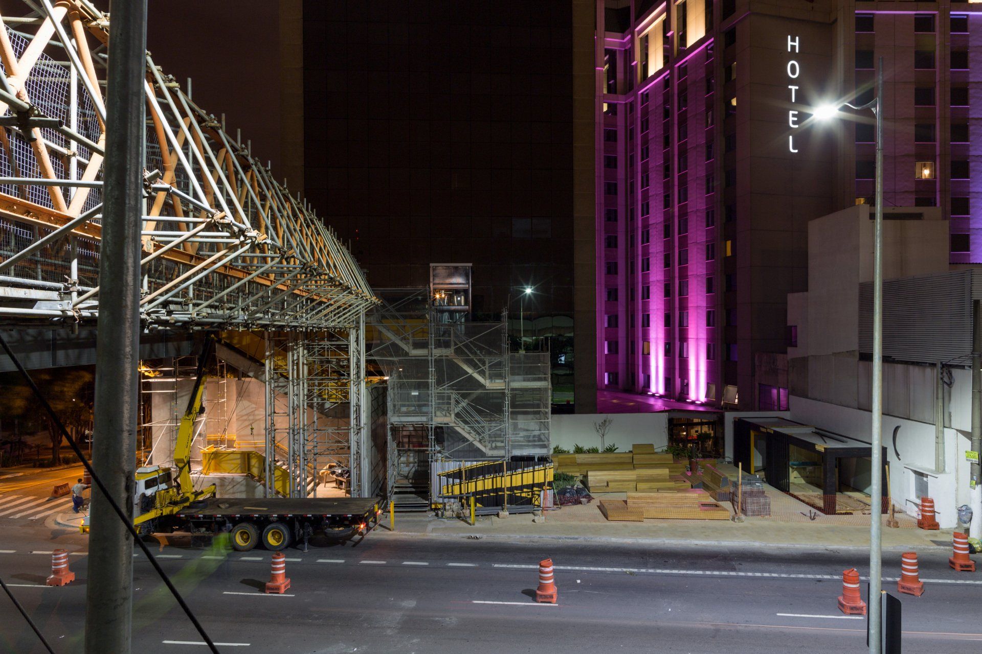 Um canteiro de obras à noite com um hotel ao fundo