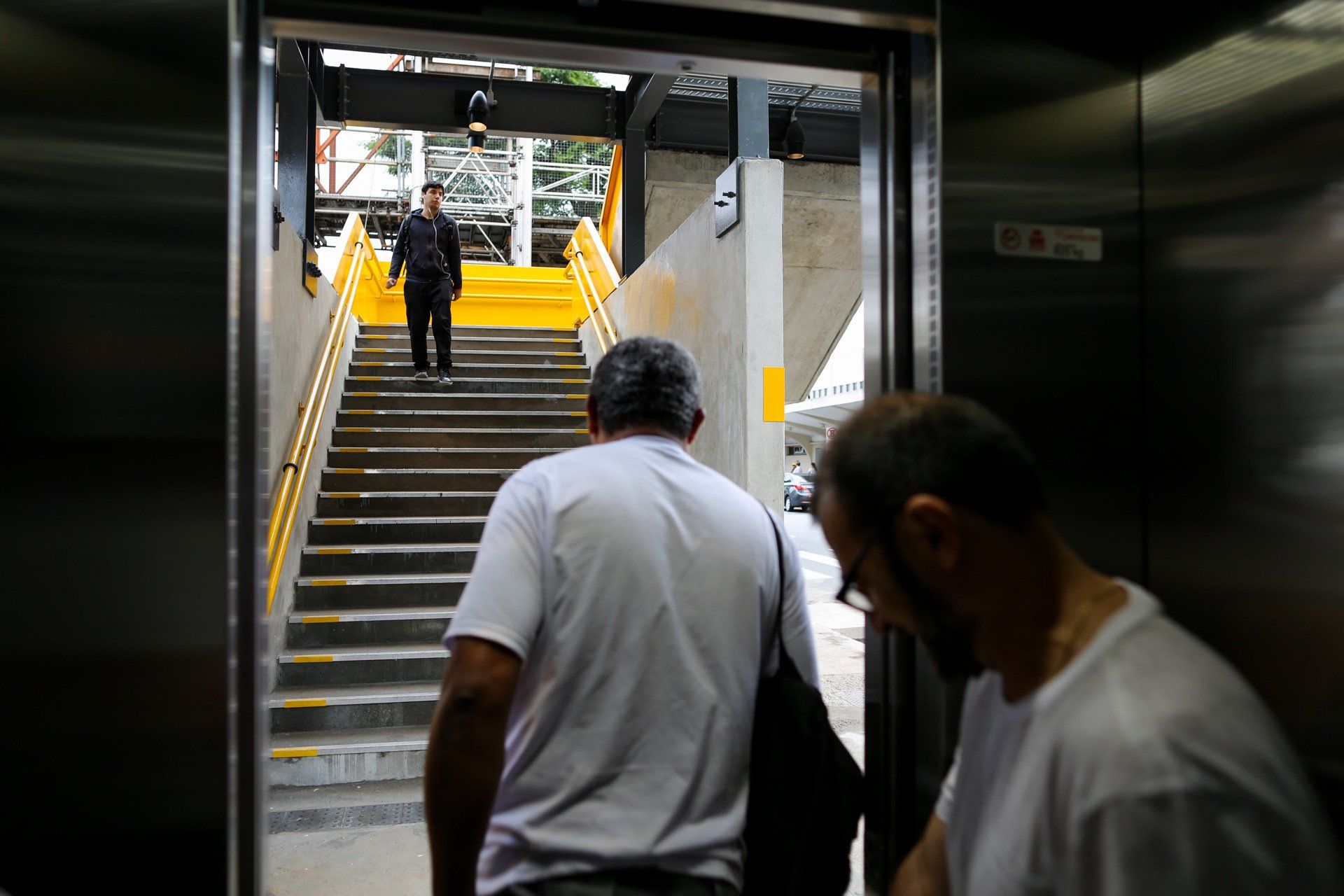Dois homens estão subindo escadas em um elevador.