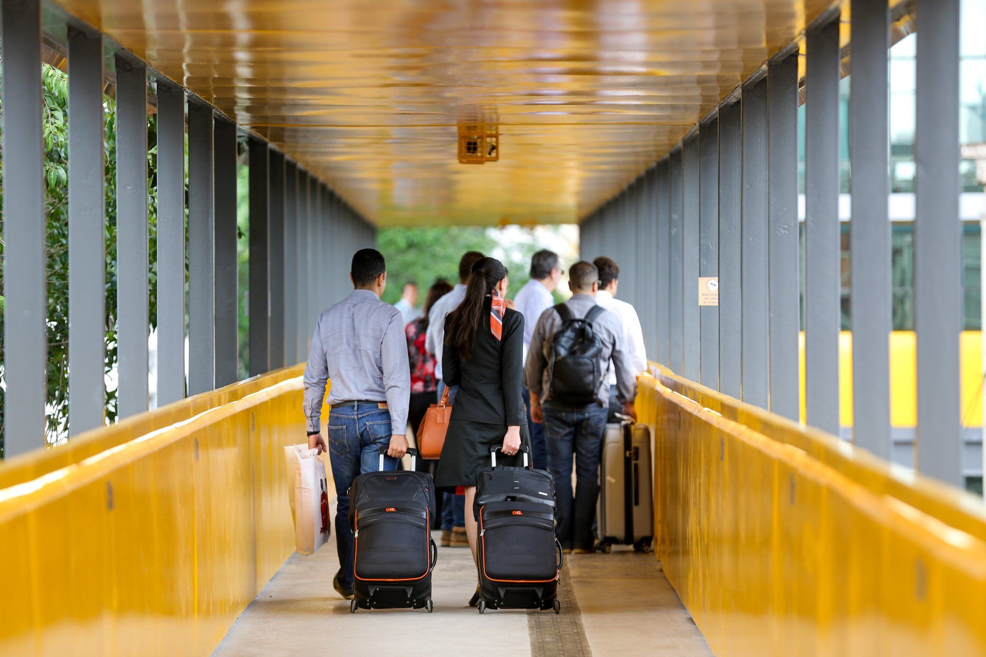 Um grupo de pessoas atravessa uma ponte com bagagens.