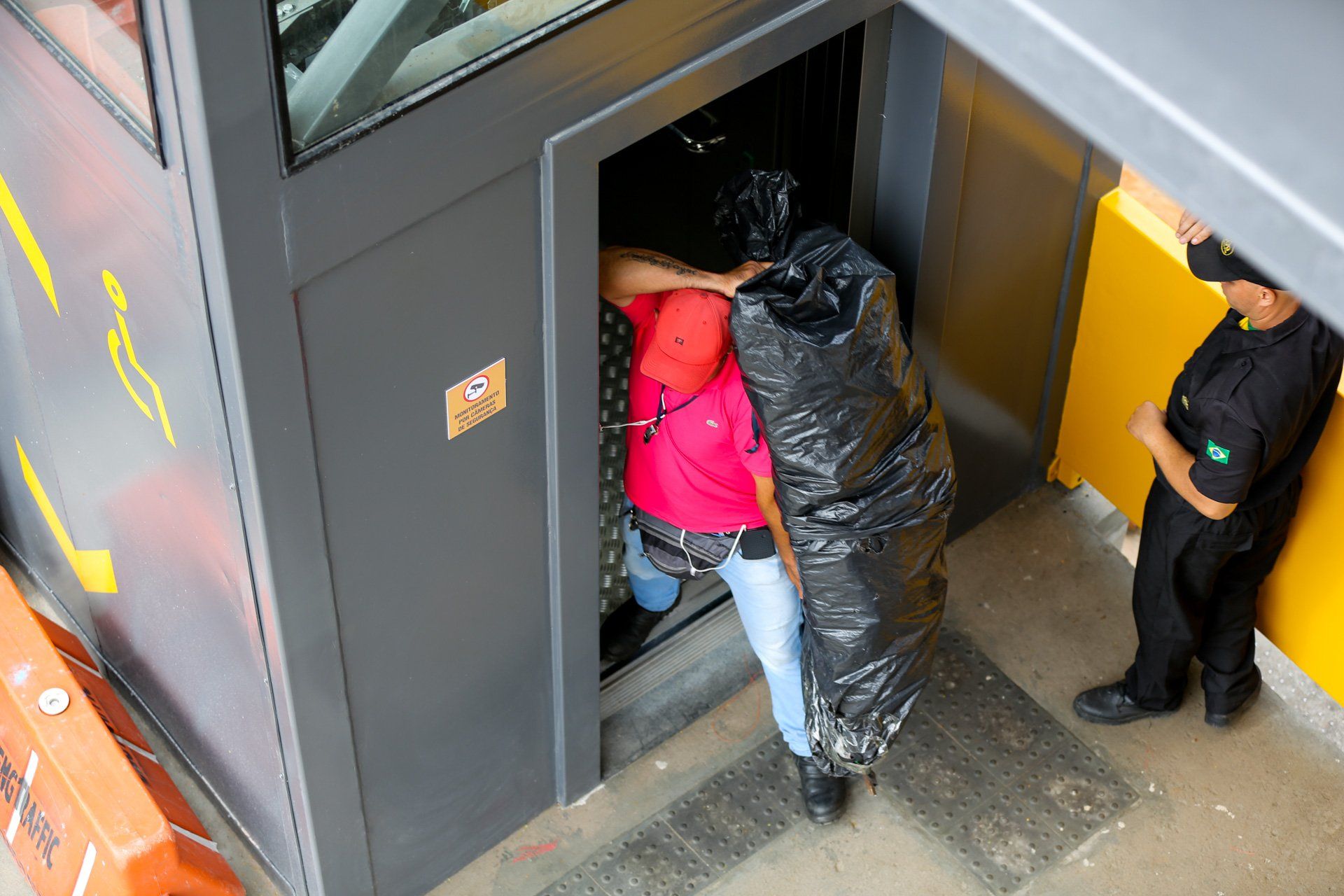 Uma mulher está carregando uma grande bolsa preta para dentro de um elevador.