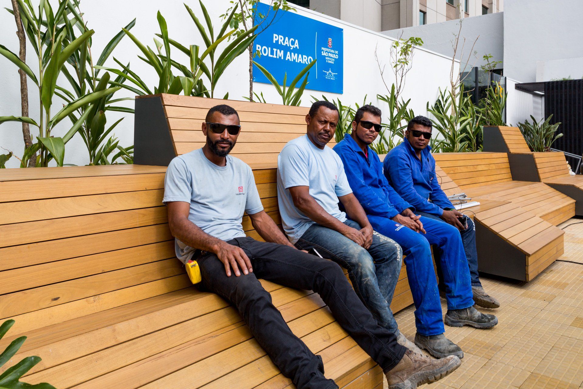 Um grupo de homens está sentado em um banco de madeira.