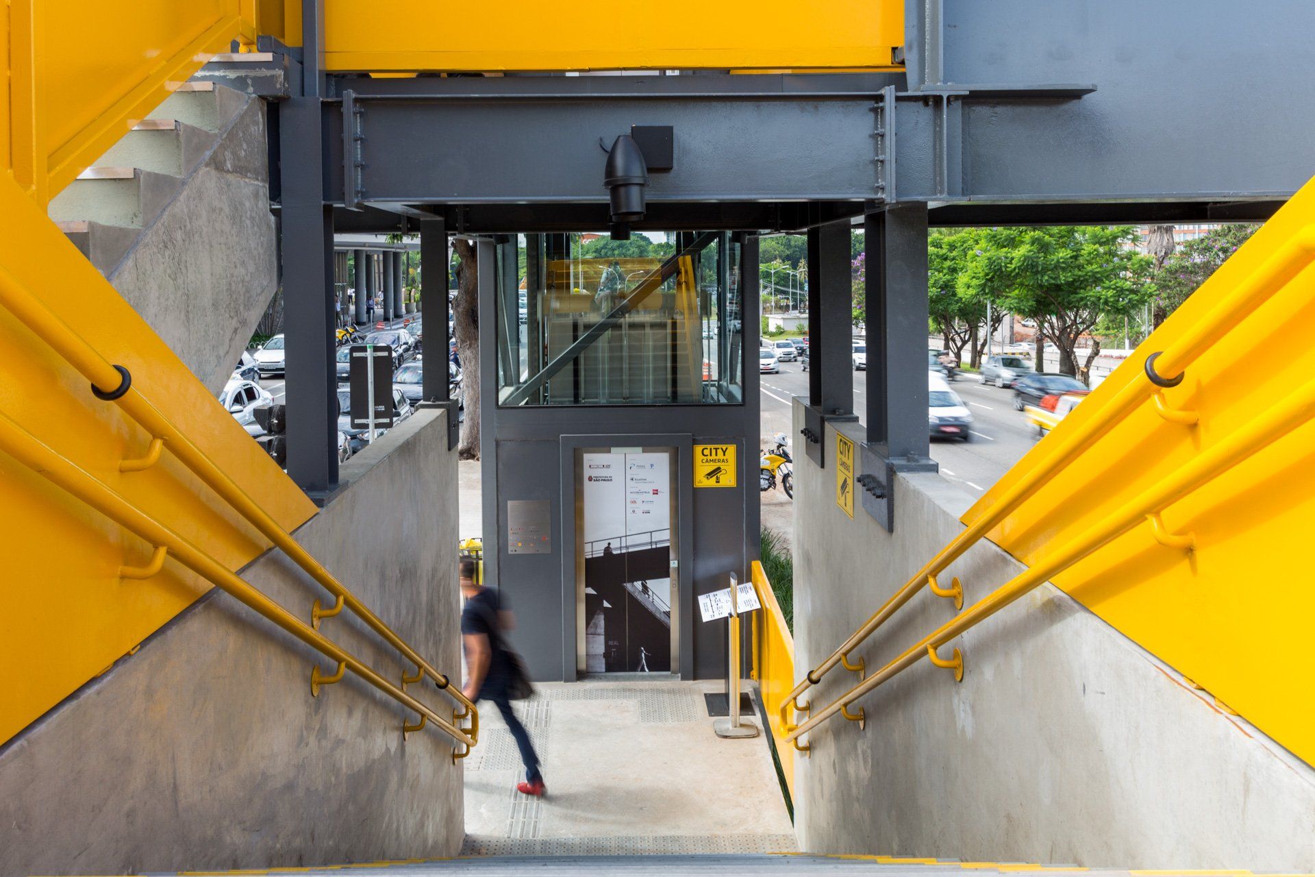 Uma pessoa está descendo uma escada ao lado de um elevador.