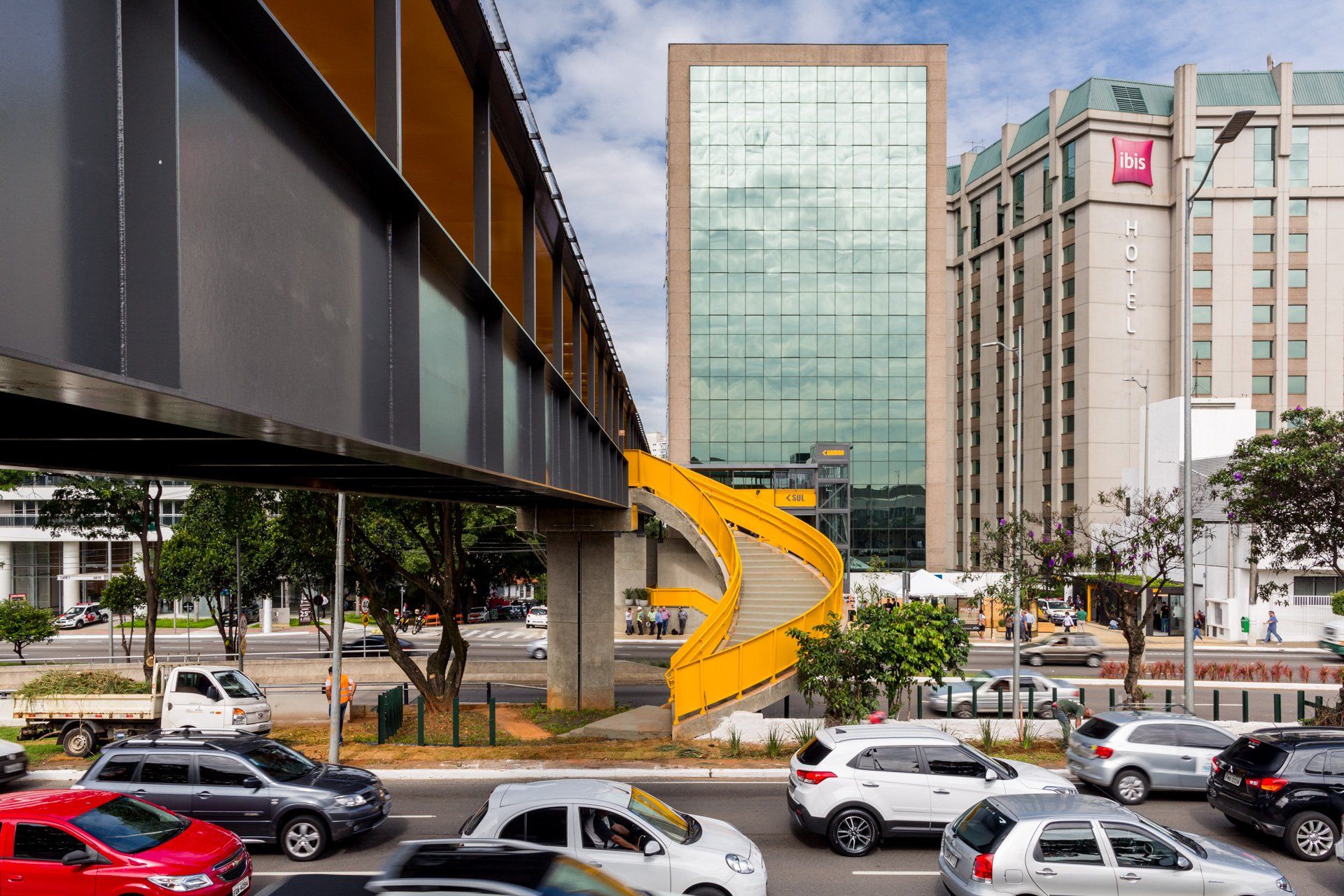 Uma ponte sobre uma rua movimentada com um grande edifício ao fundo.