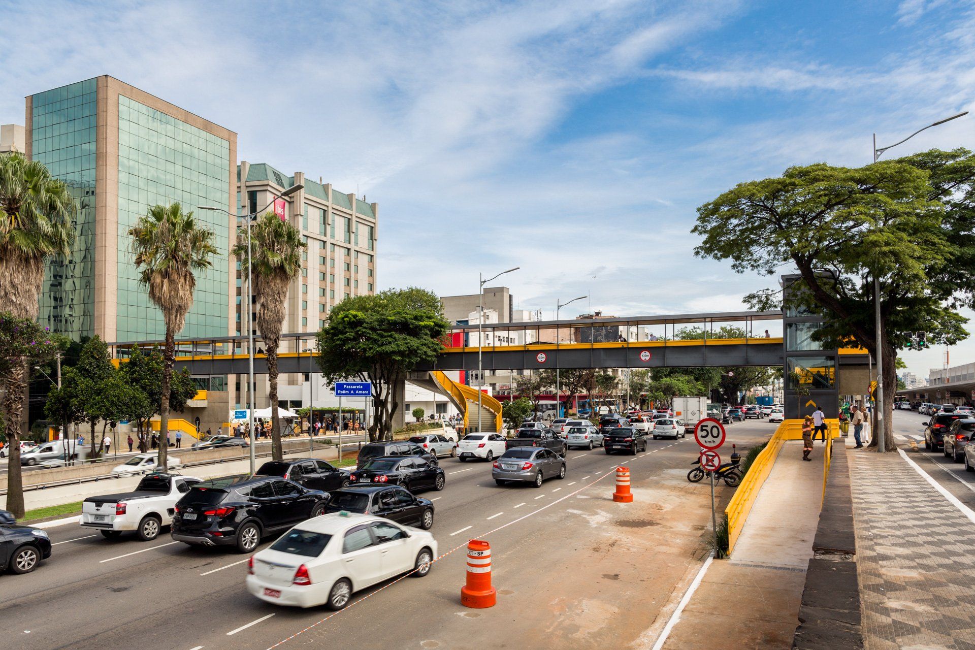 Uma rua movimentada da cidade com carros passando debaixo de uma ponte.
