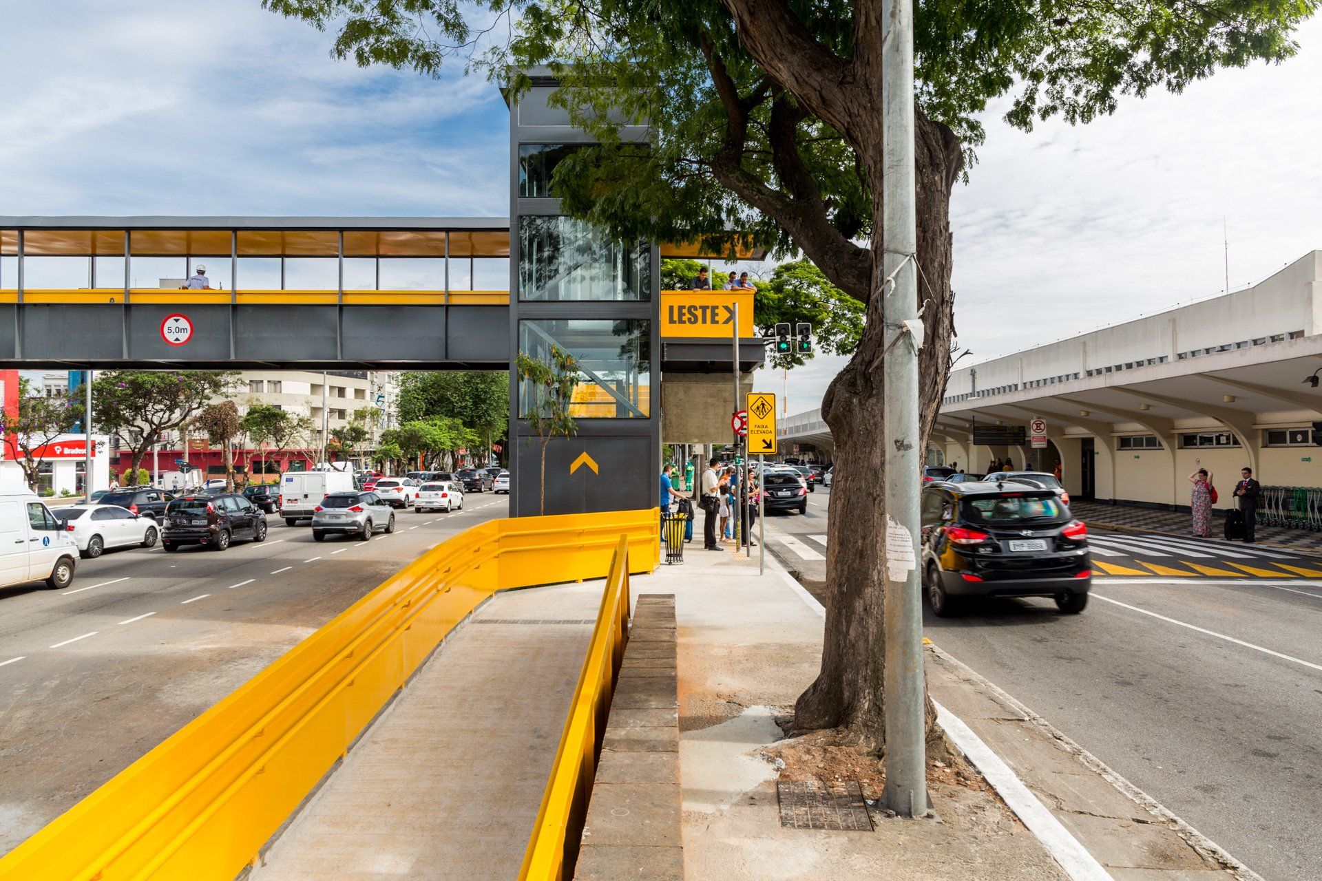 Uma rua movimentada com uma rampa amarela e uma ponte sobre ela