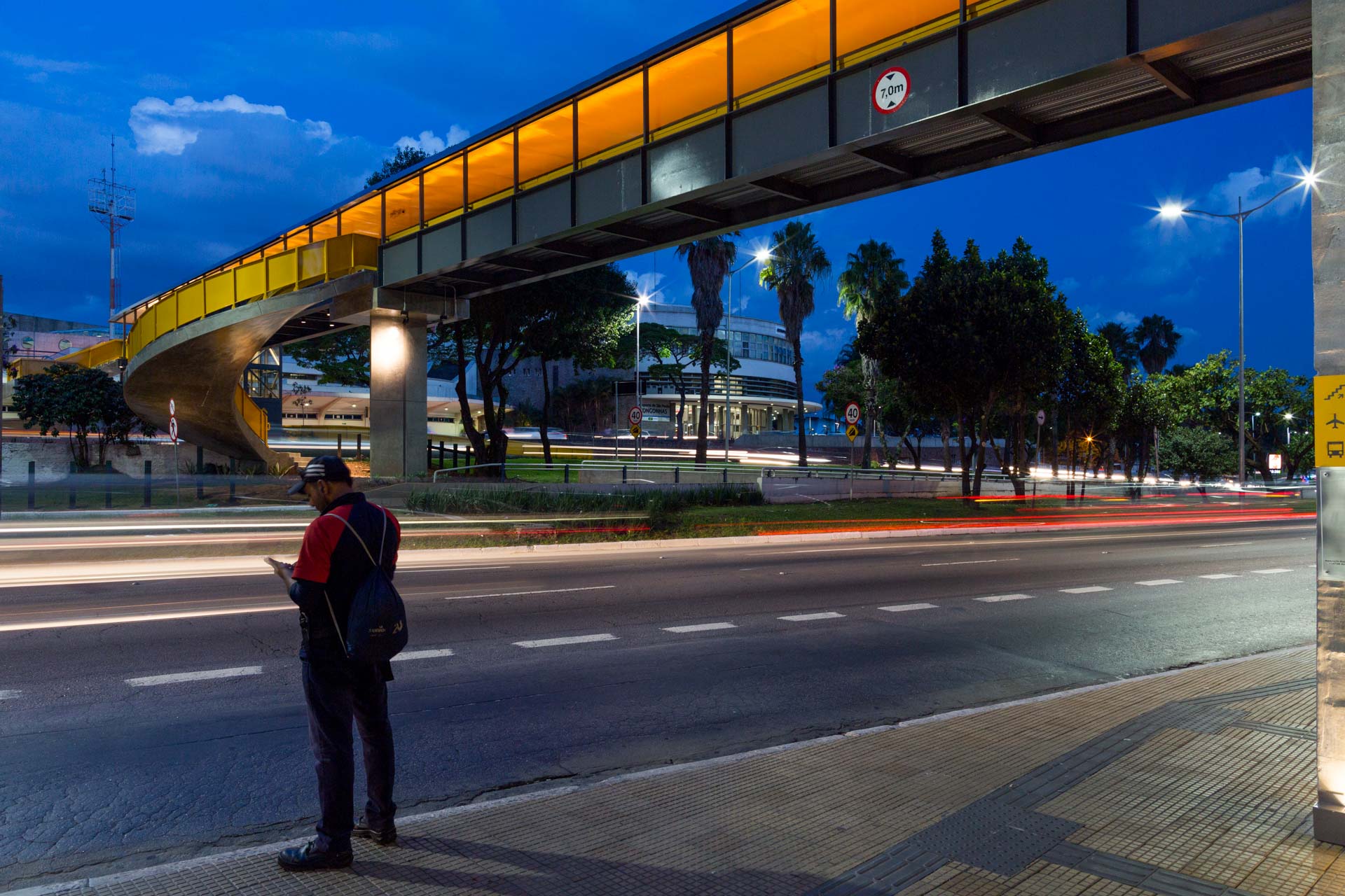 Um homem está parado na beira da estrada olhando para o telefone.