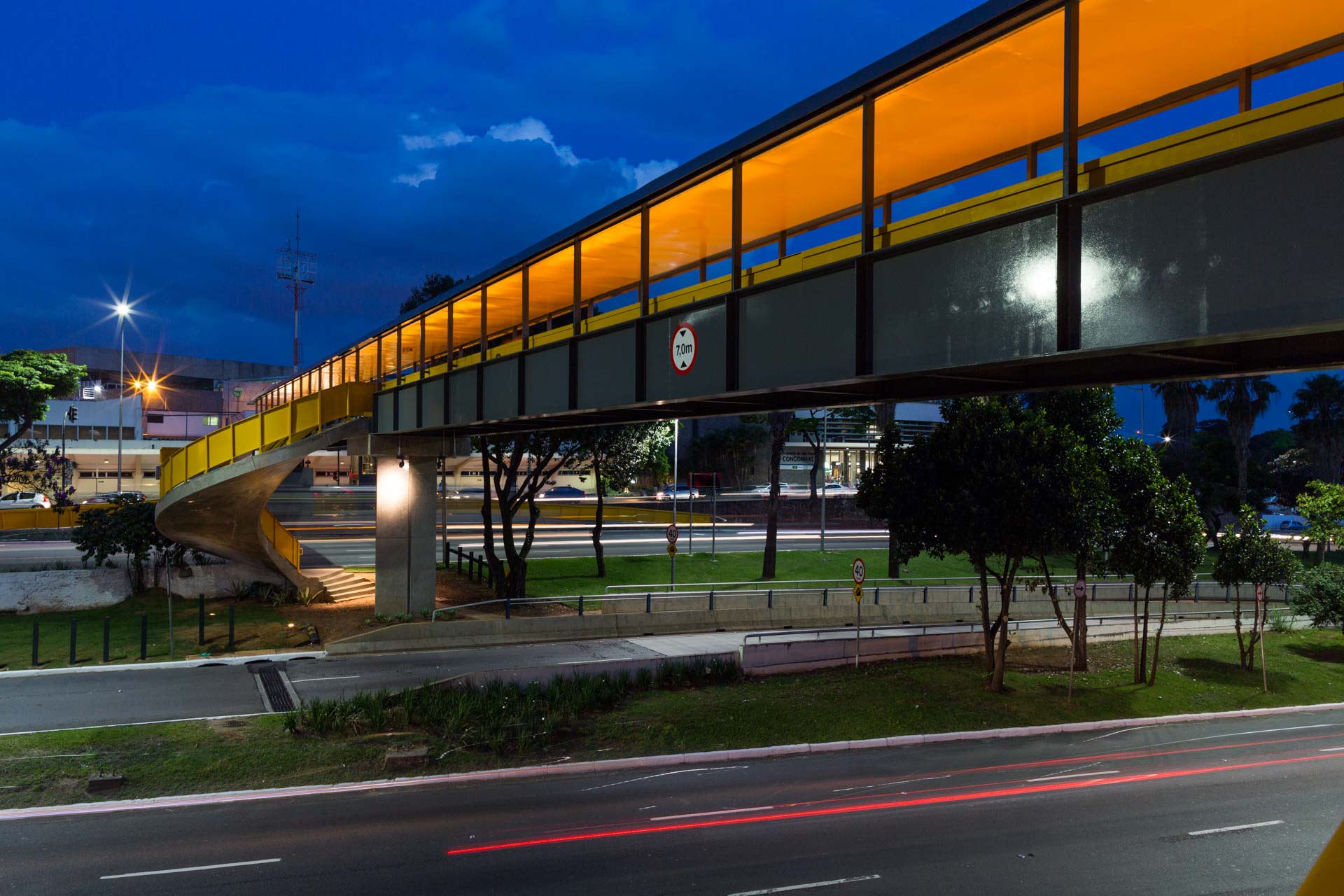 Uma ponte sobre uma estrada à noite com árvores ao fundo