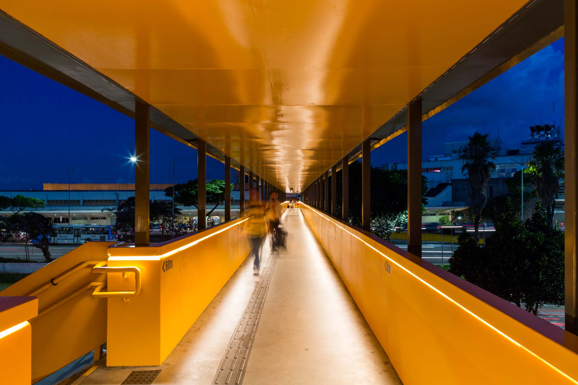 Uma pessoa está atravessando uma ponte à noite.