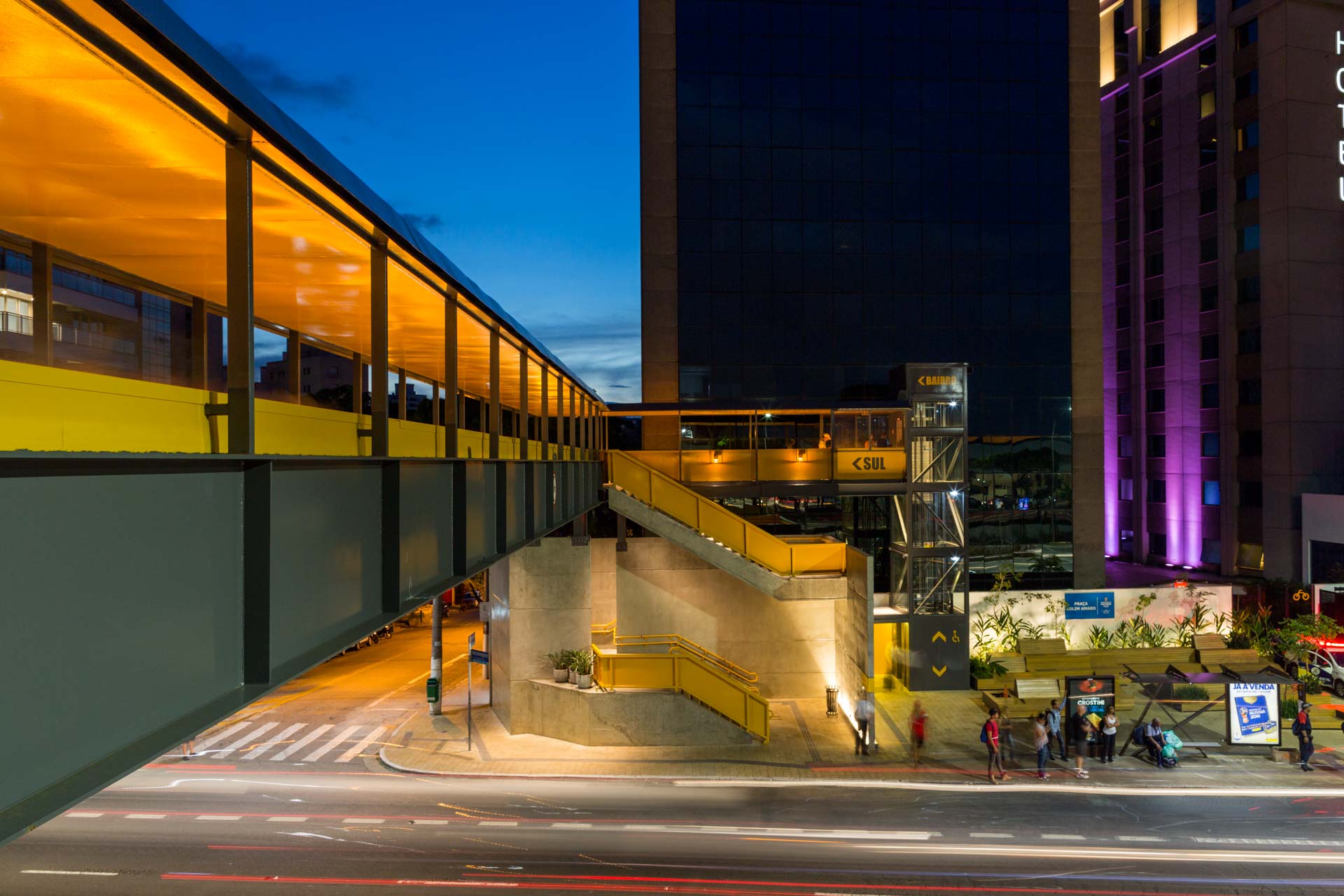 Uma ponte sobre uma rua em frente a um prédio à noite.