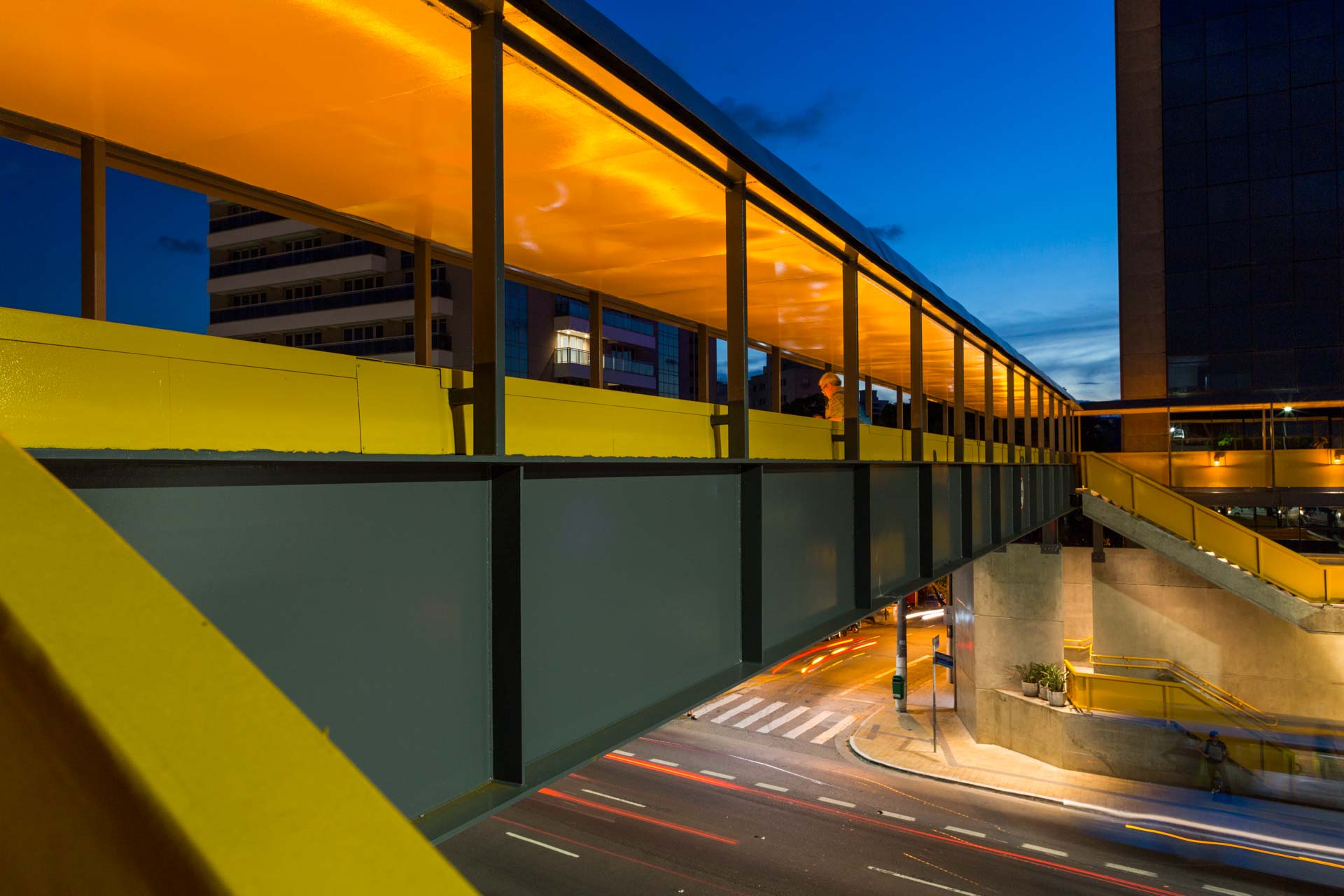 Uma ponte amarela sobre uma rua da cidade à noite.