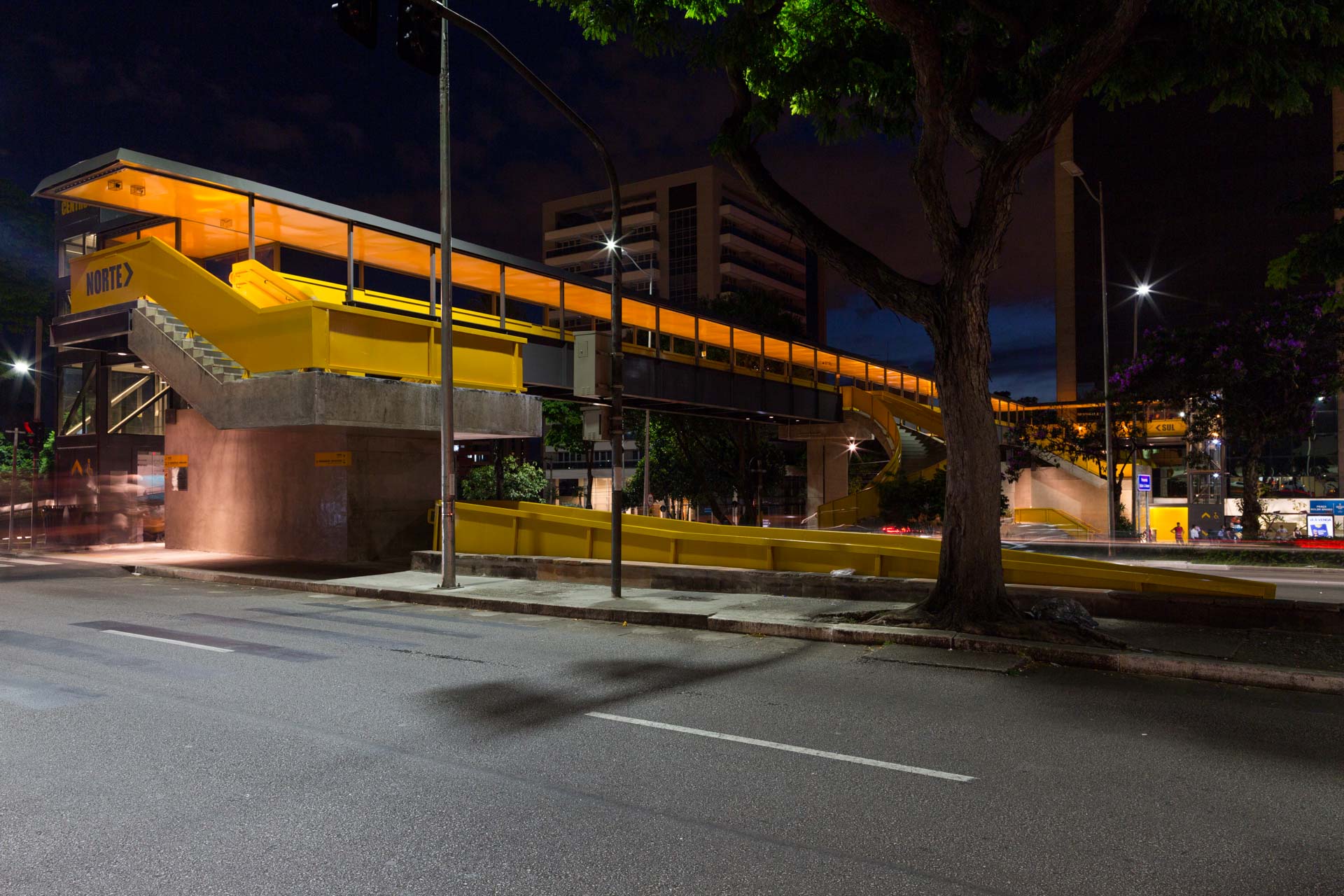 Uma rua vazia com uma ponte amarela sobre ela à noite