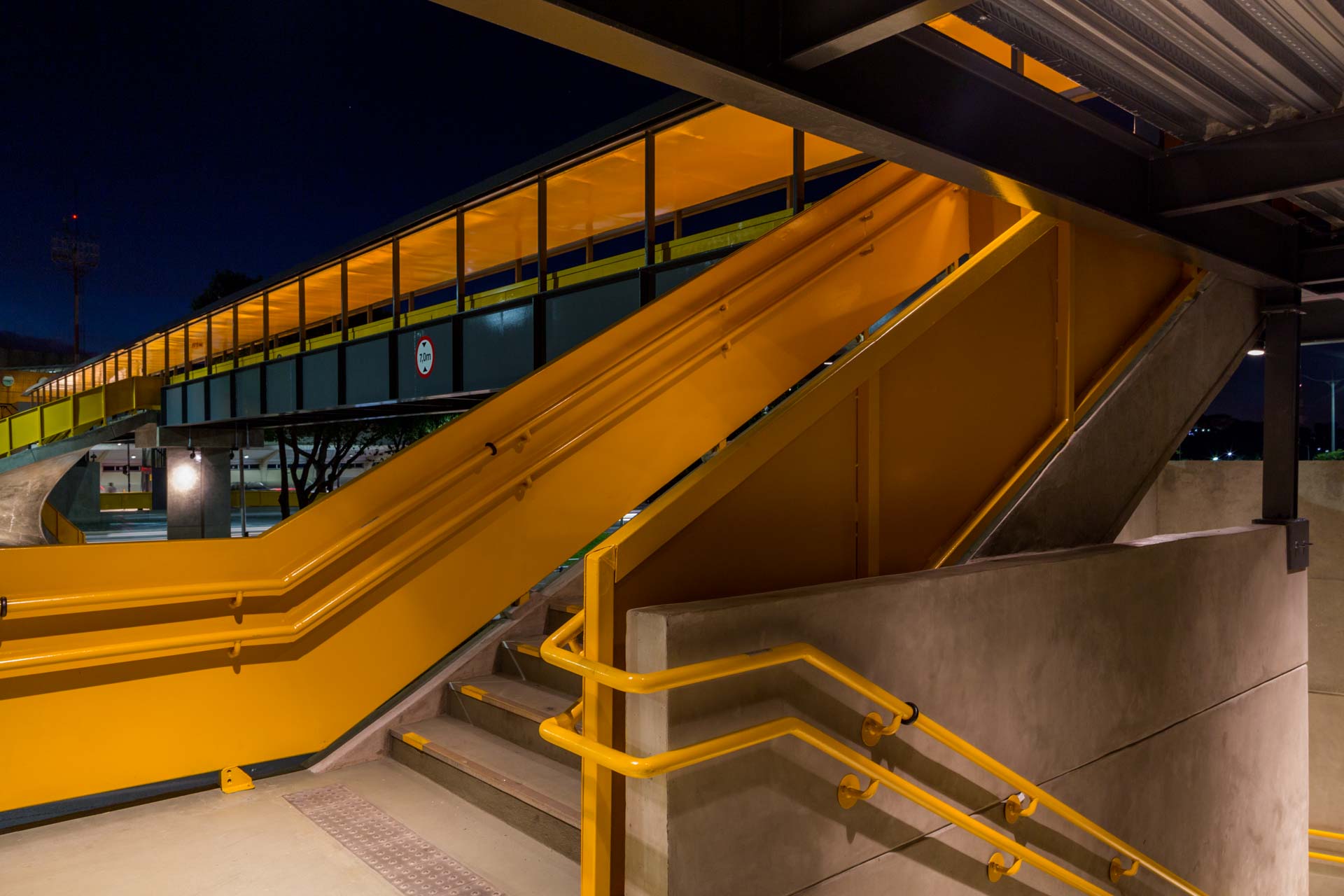 Uma escada amarela que leva a uma ponte à noite.