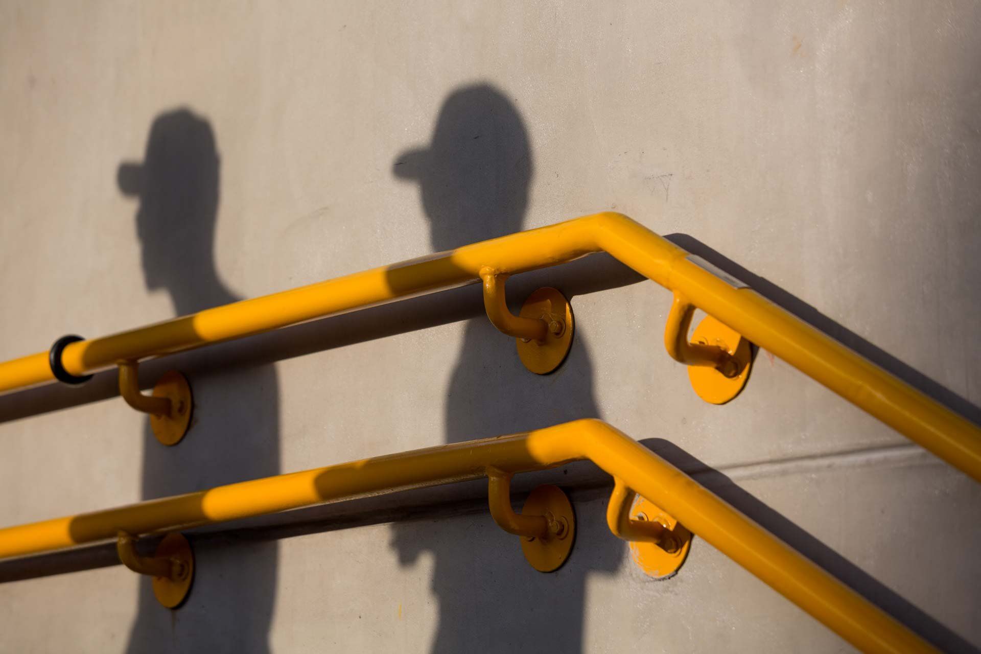 Uma sombra de uma pessoa é projetada em uma parede por uma grade amarela