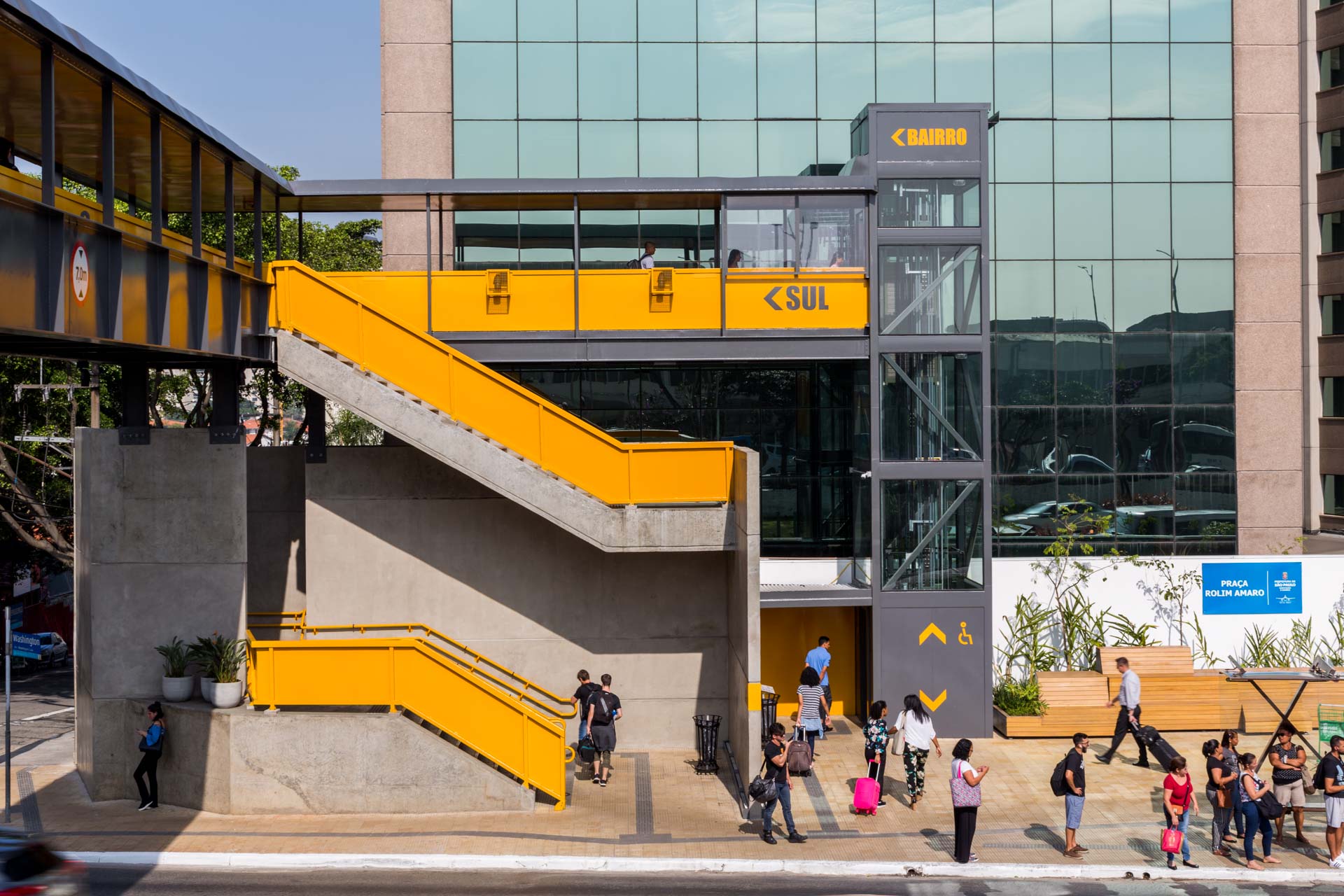 Um grupo de pessoas está do lado de fora de um prédio com escadas que levam até ele.