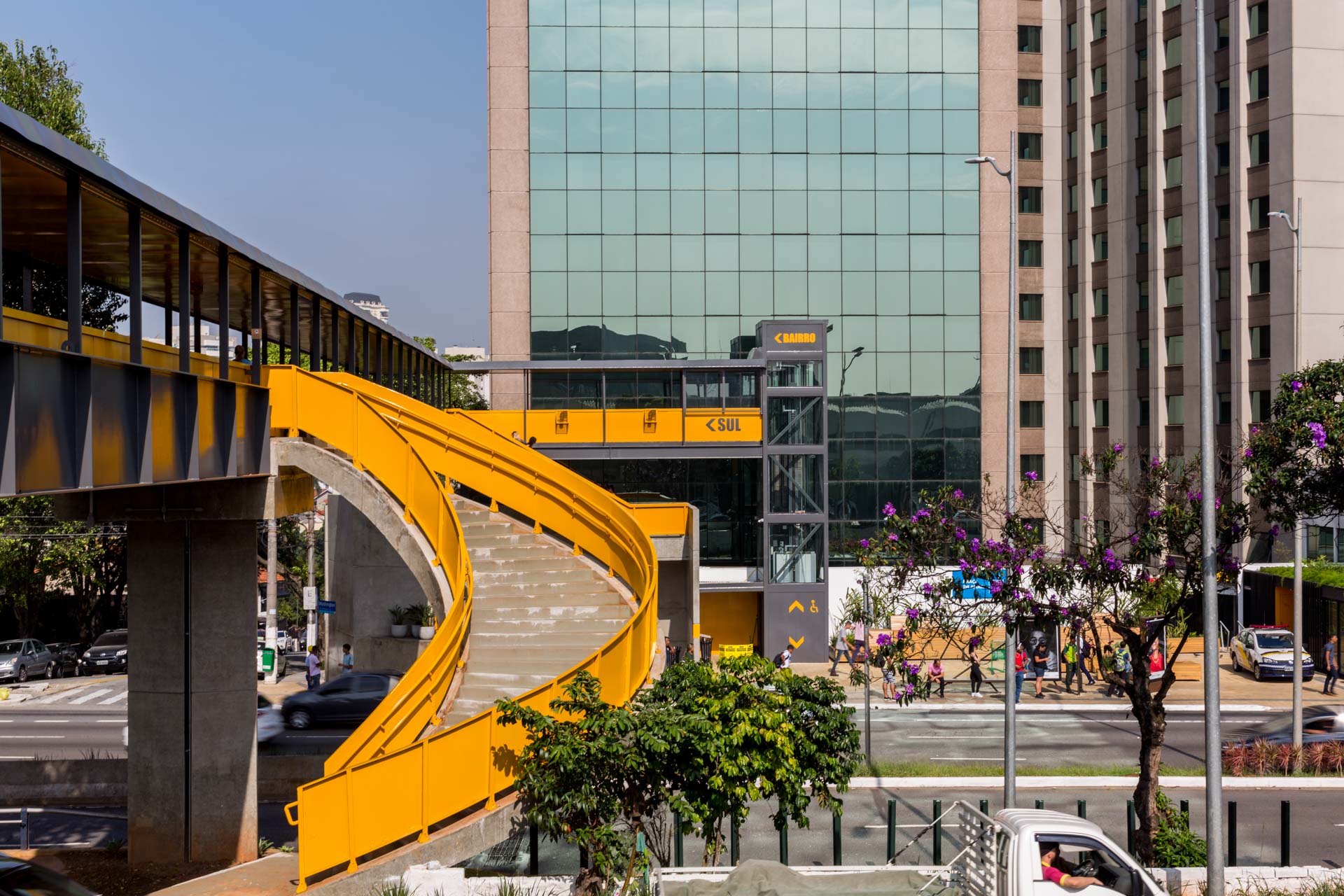 Uma ponte amarela passa por uma rua em frente a um prédio.