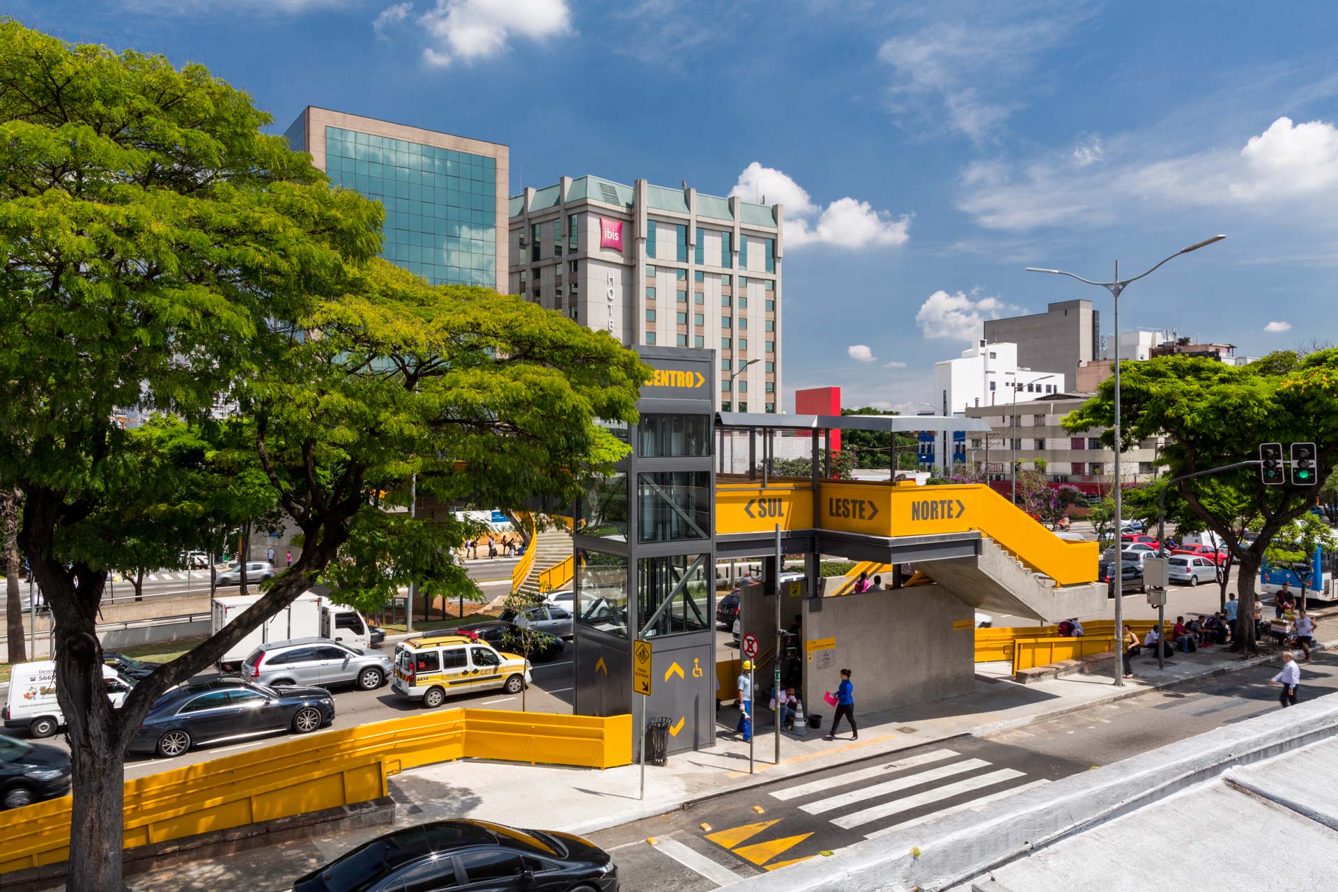 Uma vista aérea de uma rua da cidade com árvores e edifícios ao fundo.