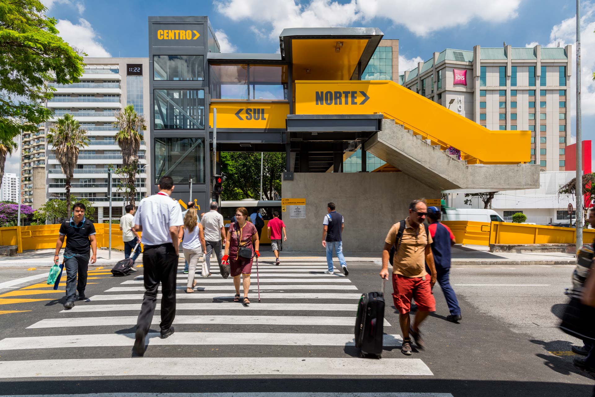 Um grupo de pessoas atravessa uma rua em frente a um prédio que diz norte