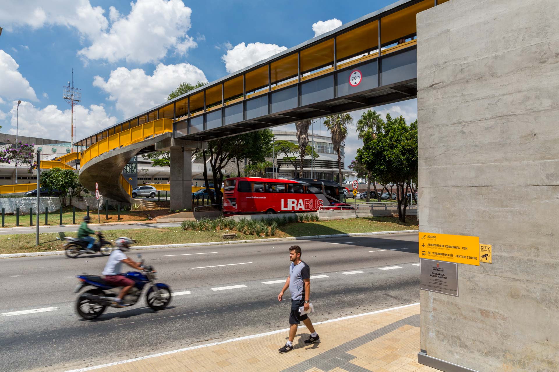 Um homem está atravessando uma rua próximo a uma ponte.
