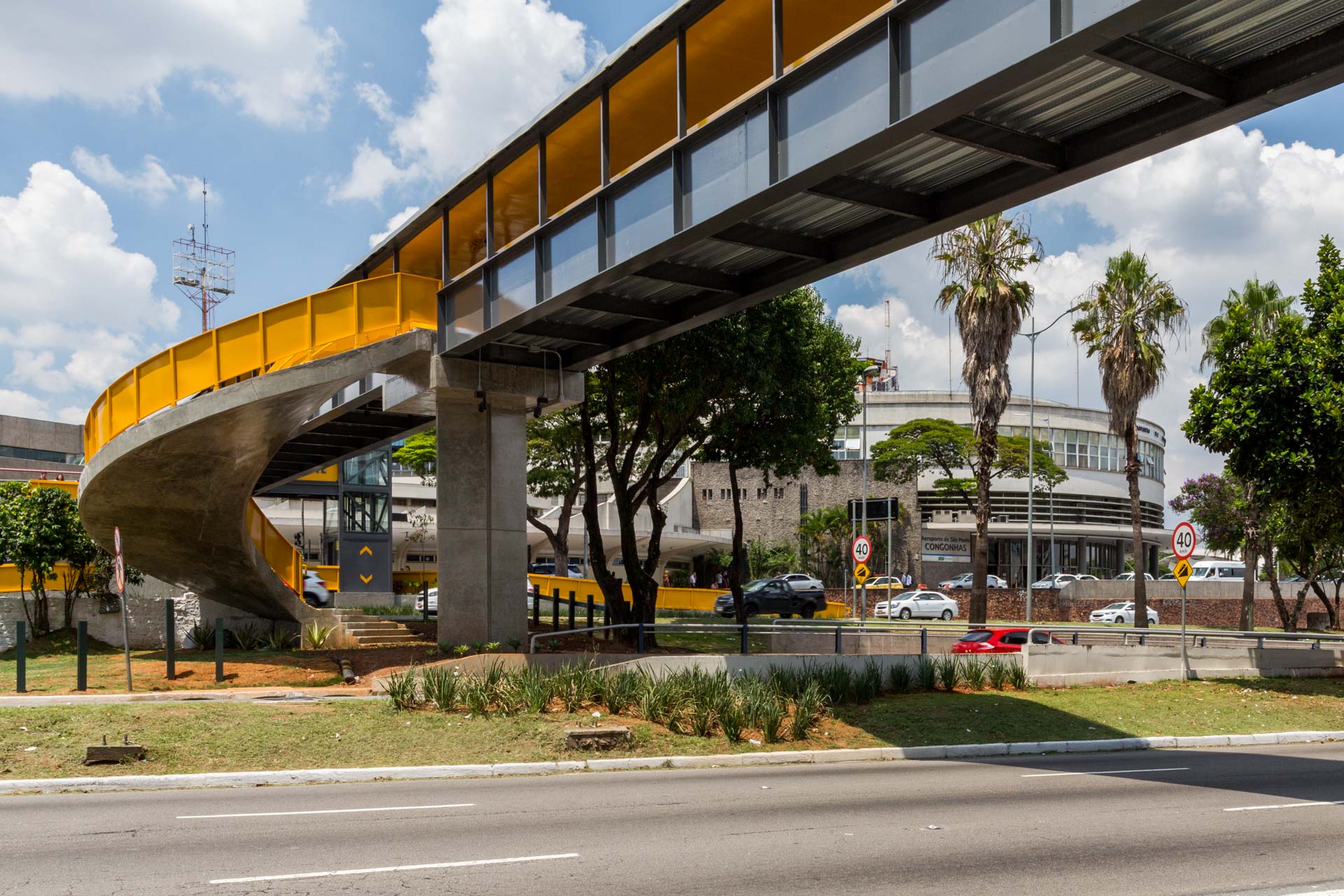 Uma ponte amarela sobre uma estrada com árvores ao fundo