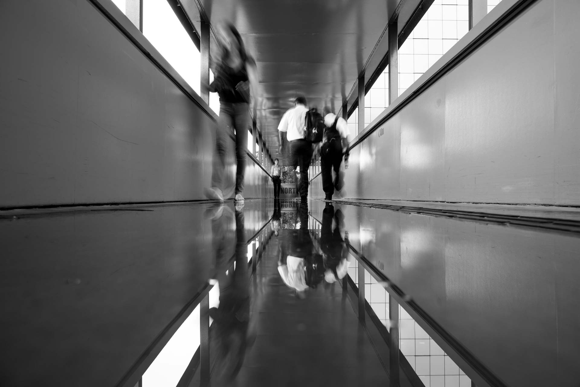 Uma foto em preto e branco de pessoas andando por um corredor