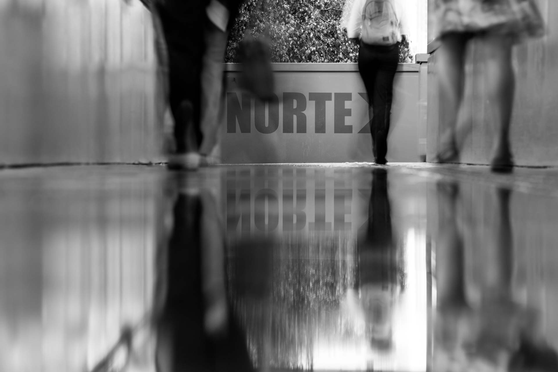 Um grupo de pessoas caminha por um corredor em uma foto em preto e branco.