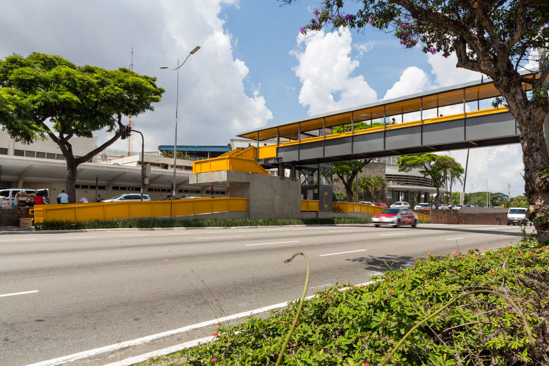 Um carro vermelho está passando sob uma ponte amarela