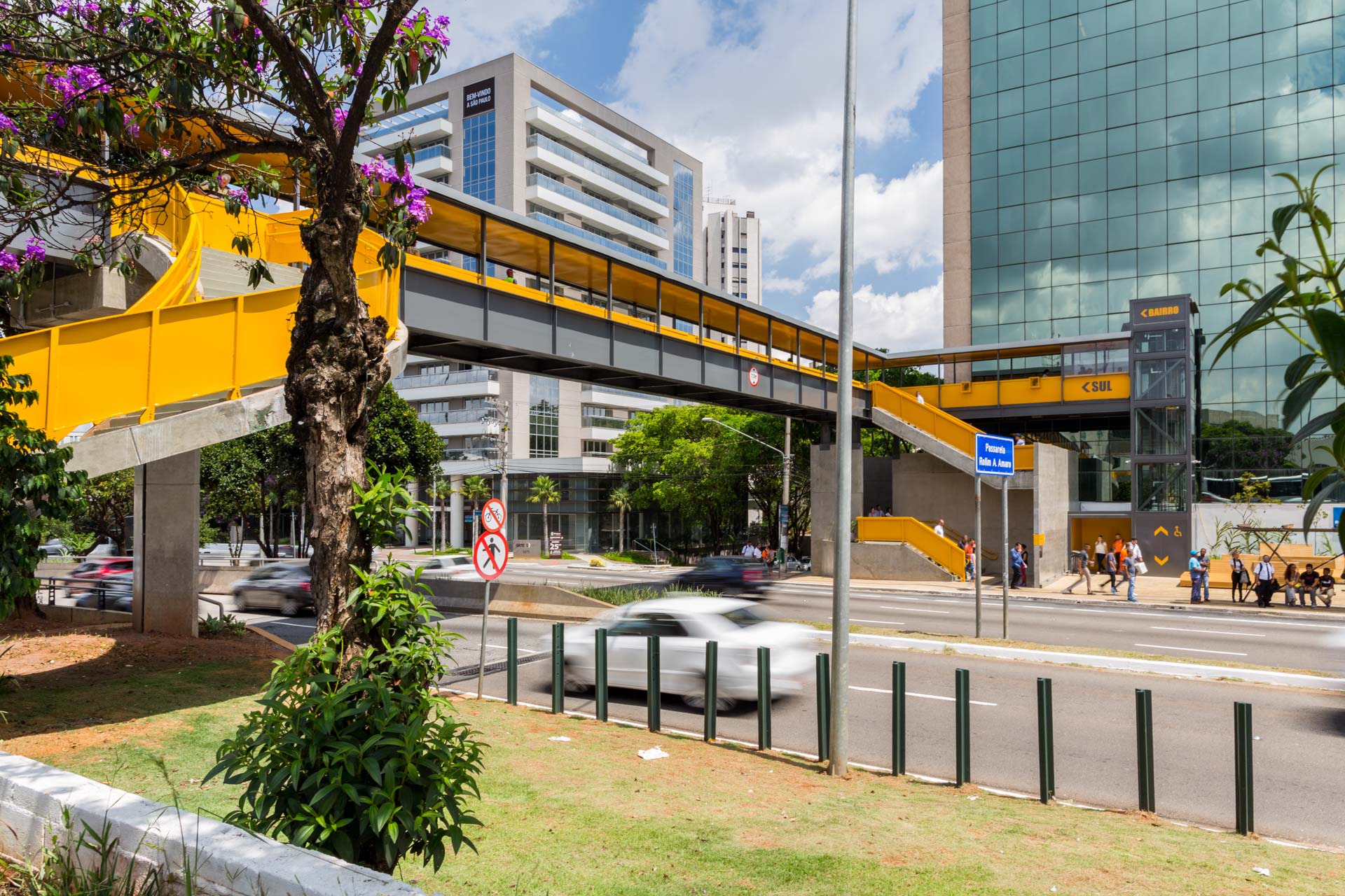 Uma ponte amarela sobre uma rua com um prédio ao fundo