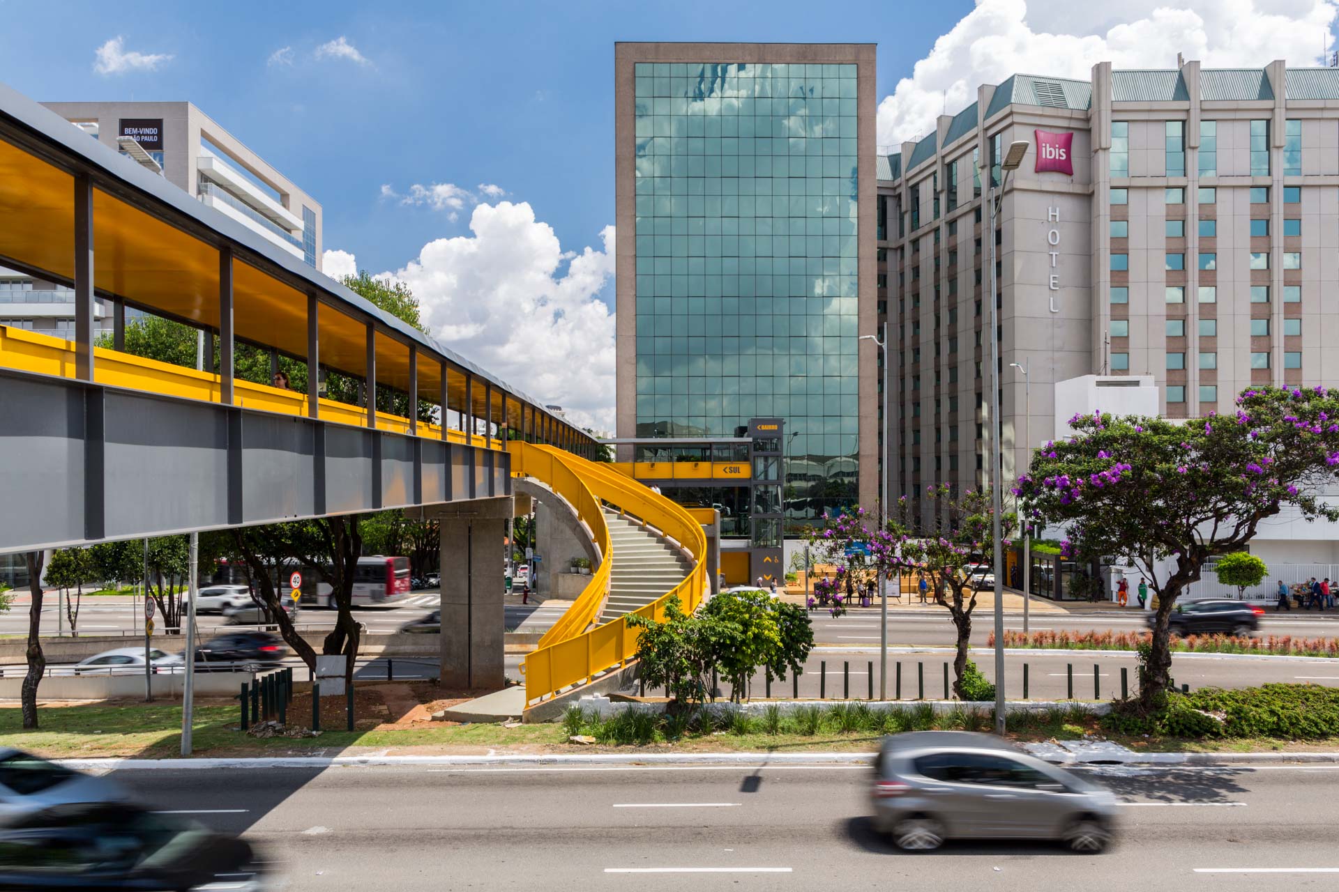 Uma ponte amarela sobre uma rua em frente a um prédio.