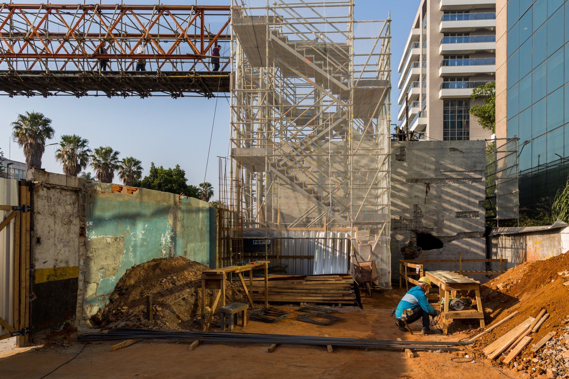 Um canteiro de obras com andaimes e um guindaste ao fundo.