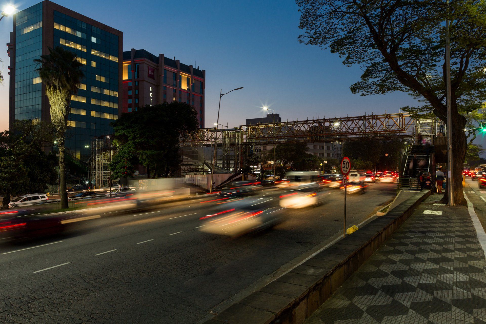 Uma imagem borrada de uma rua de uma cidade à noite com carros passando por ela.