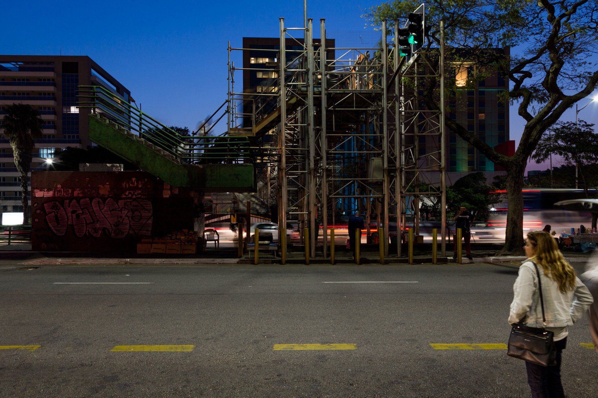 Uma mulher está atravessando a rua em frente a um prédio em construção