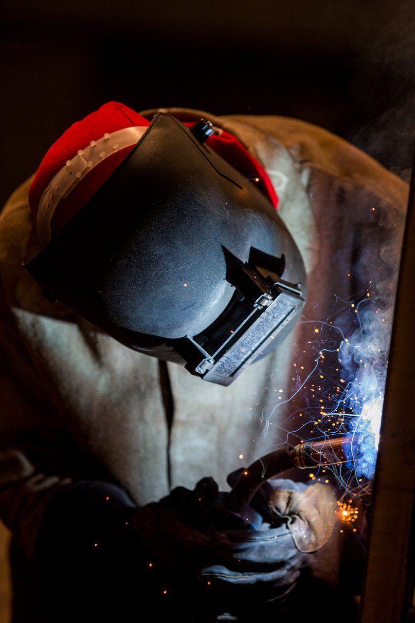 Um homem usando um capacete de soldador está soldando um pedaço de metal.