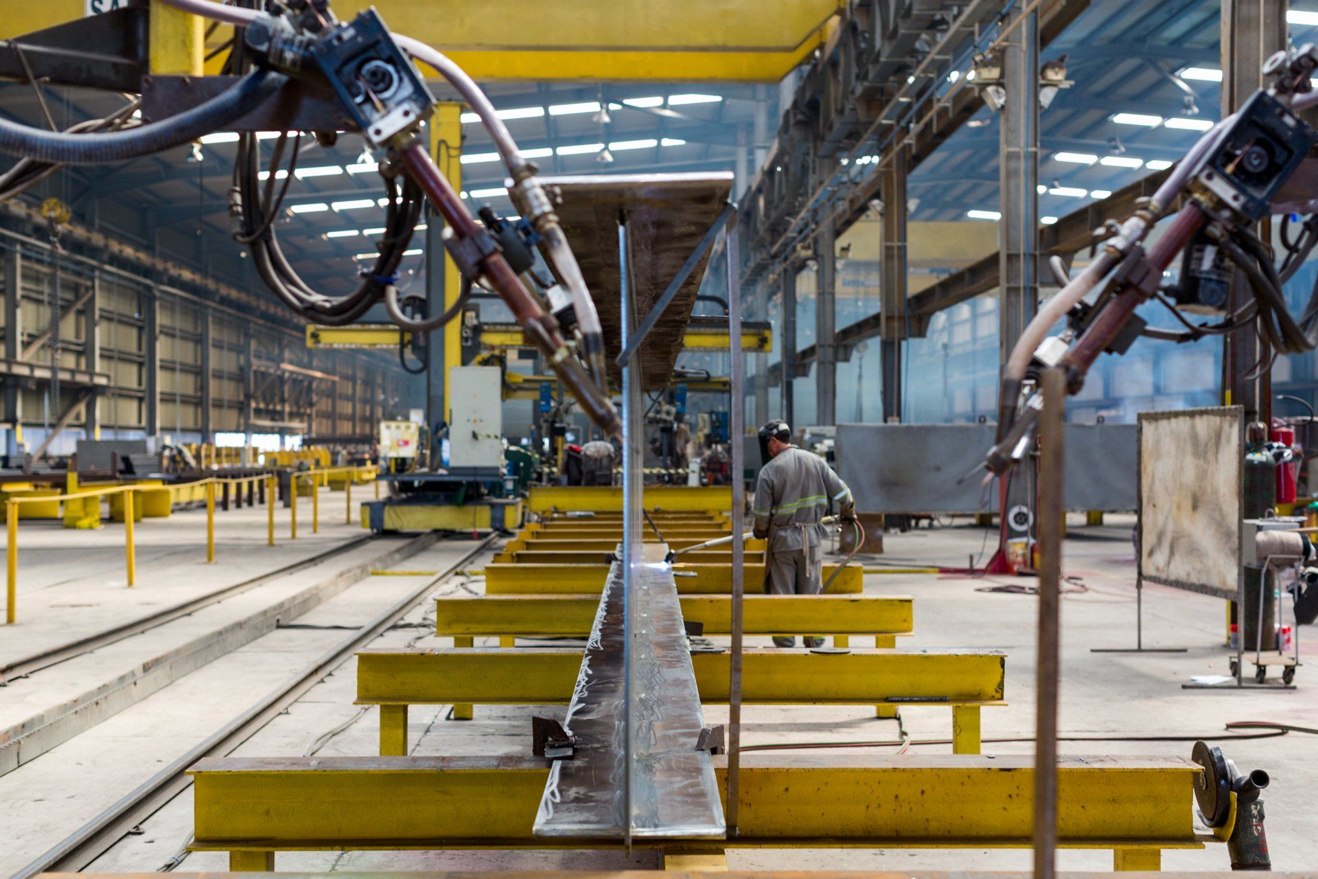 Um homem está trabalhando em um pedaço de metal em uma fábrica.