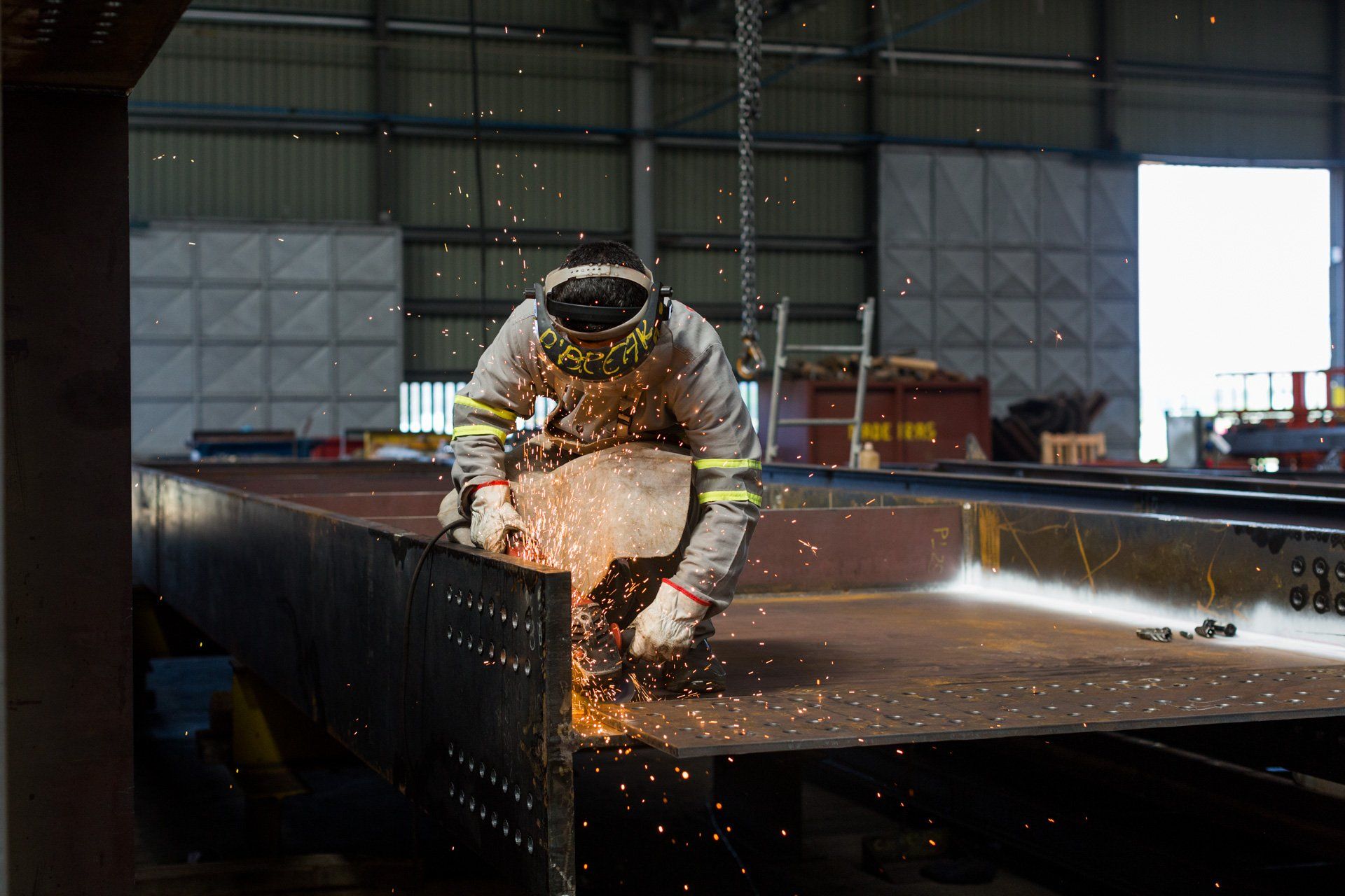 Um homem está soldando um pedaço de metal em uma fábrica.