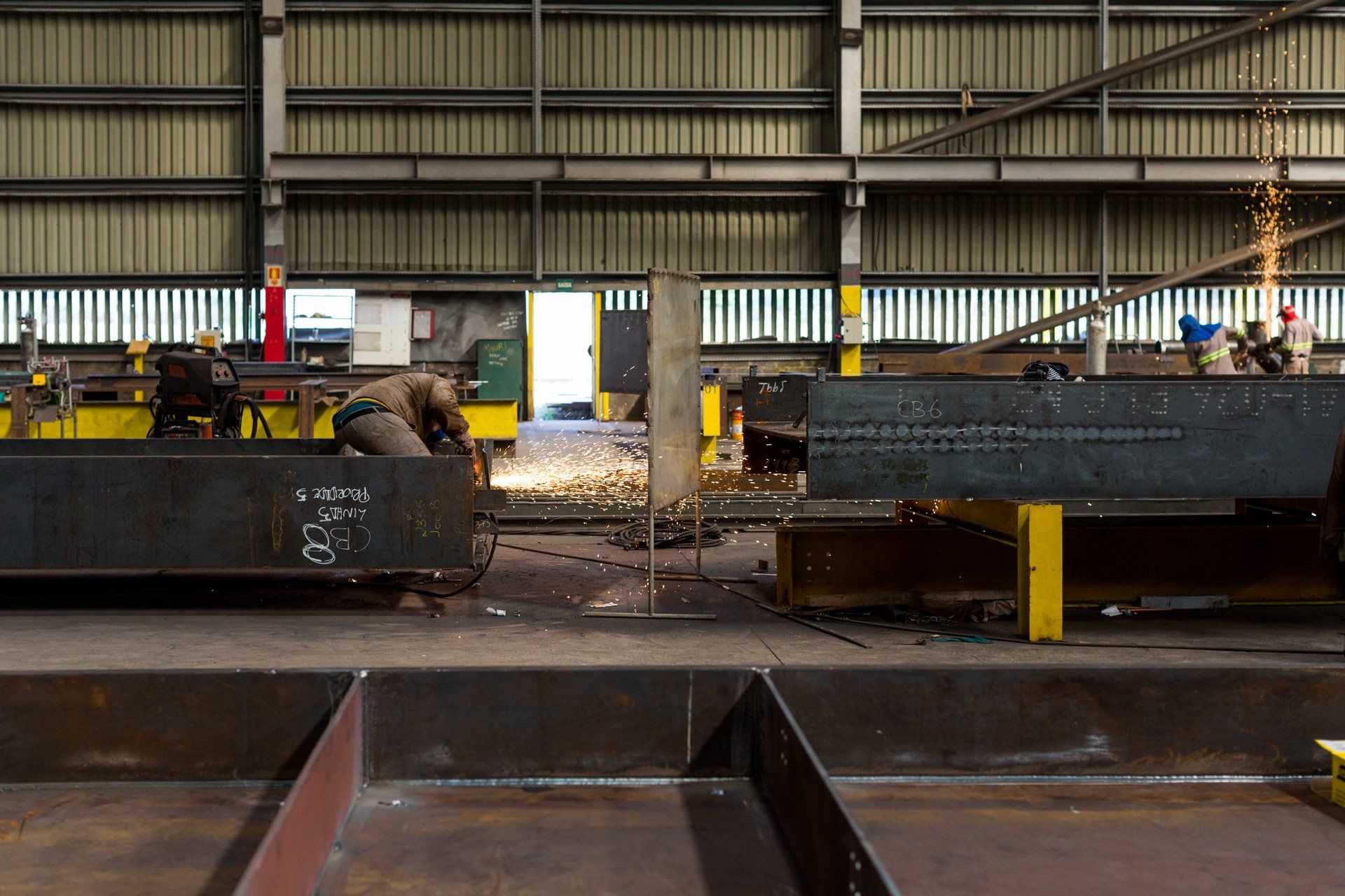 Um homem está soldando um pedaço de metal em uma fábrica.