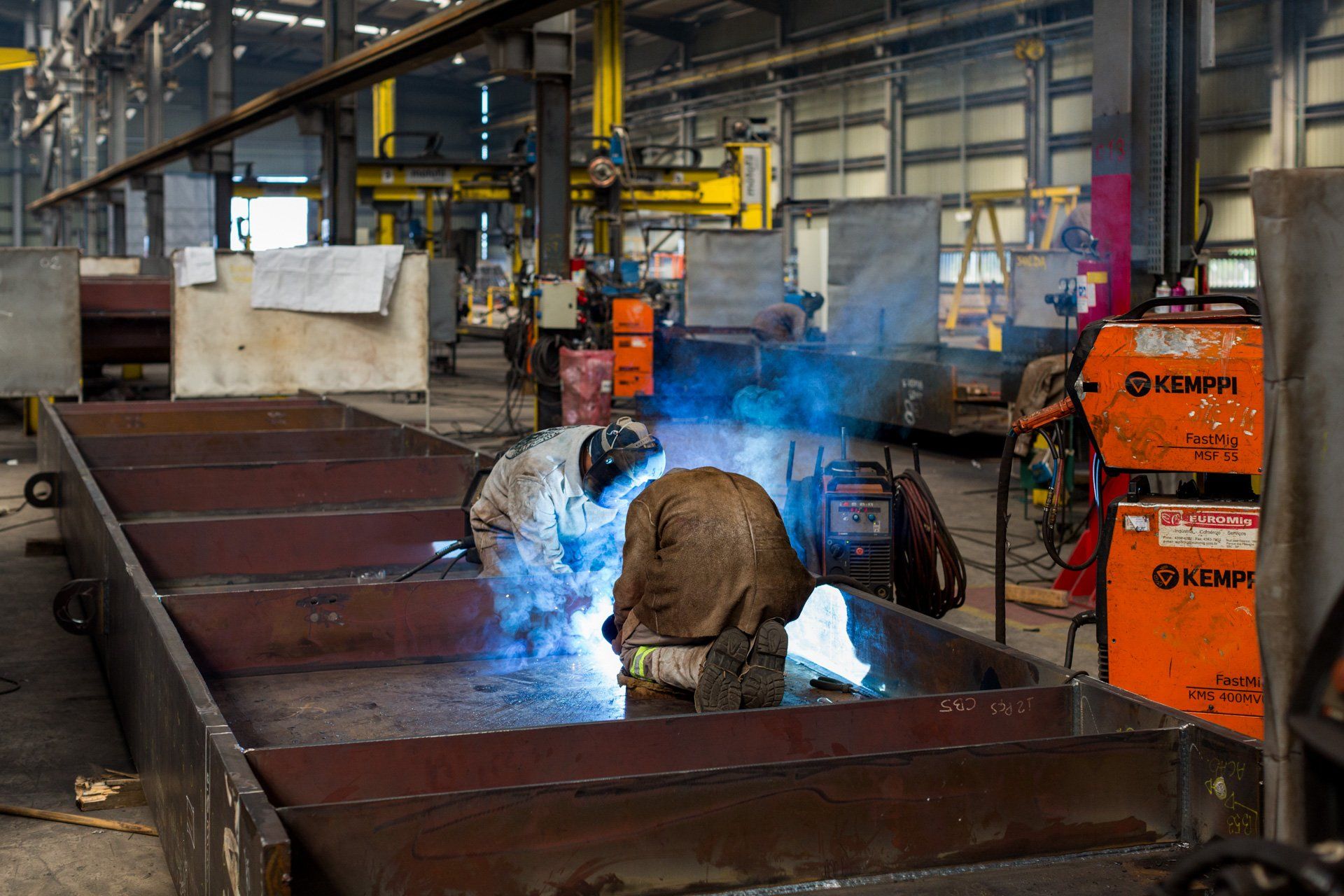 Um homem está soldando um pedaço de metal em uma fábrica.