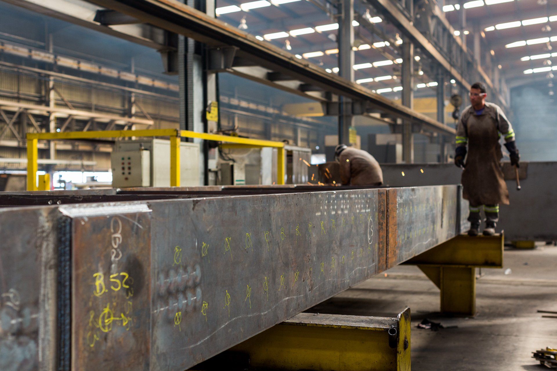 Um homem está trabalhando em uma grande peça de metal em uma fábrica.