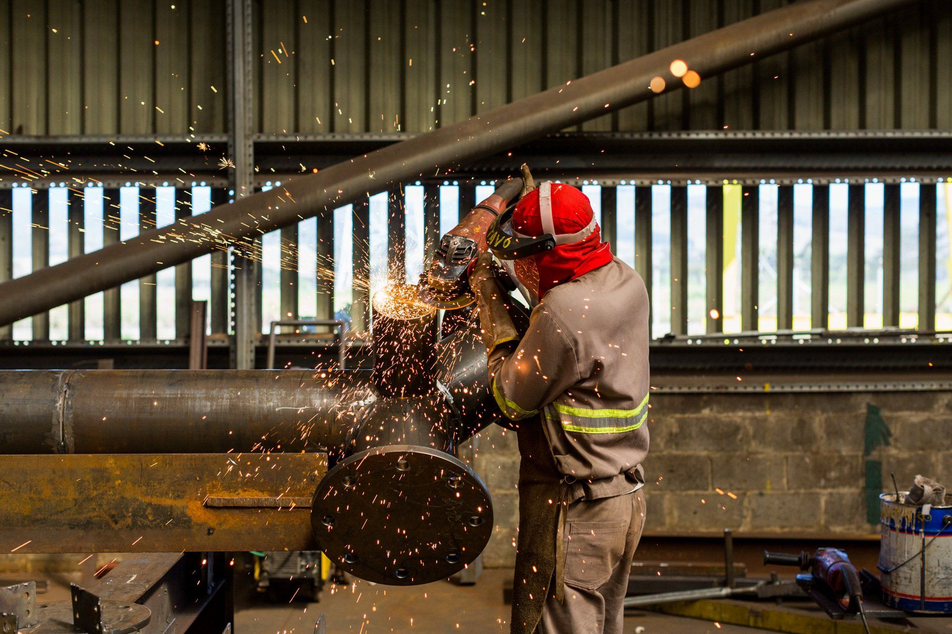 Um homem está cortando um tubo de metal com um moedor em uma fábrica.