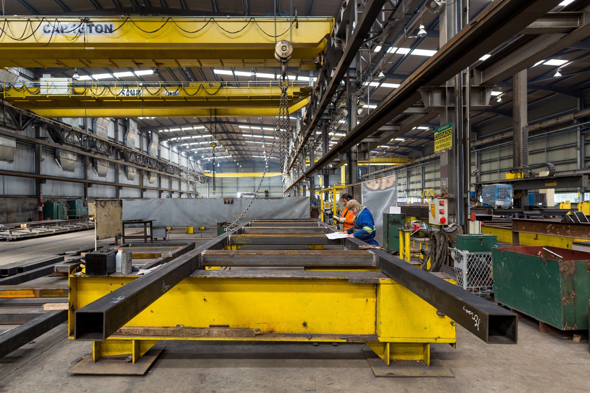 Um homem está trabalhando em um pedaço de metal em uma fábrica.