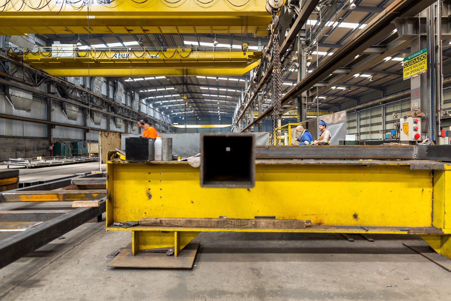 Uma grande estrutura de metal amarelo está instalada em uma fábrica.