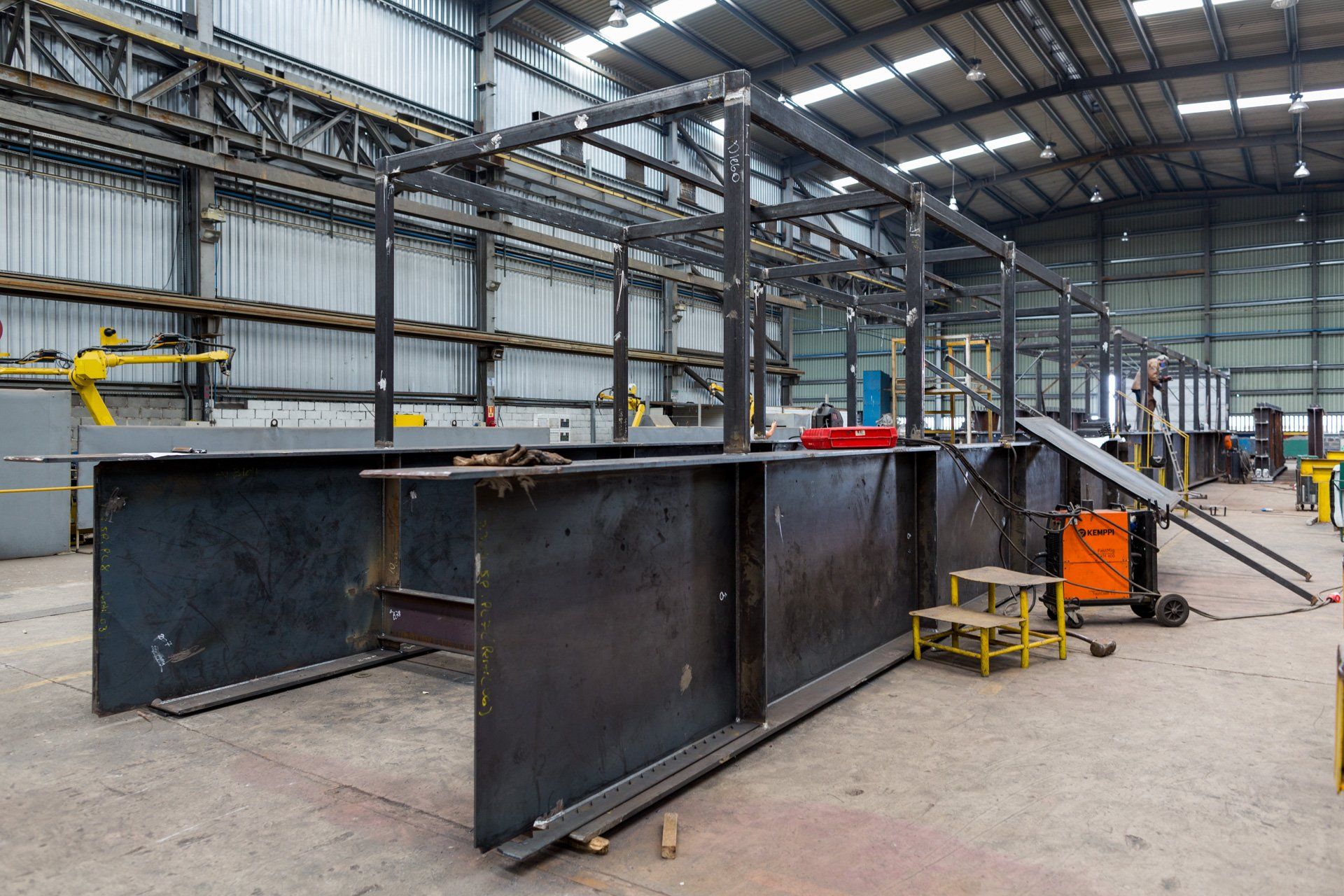 Uma grande estrutura metálica está sendo construída em uma fábrica.