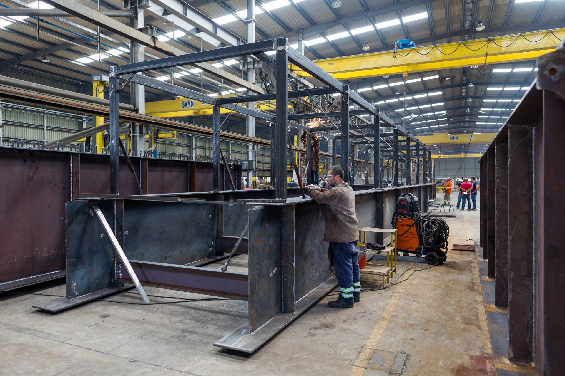 Um homem está trabalhando em uma grande estrutura metálica em uma fábrica