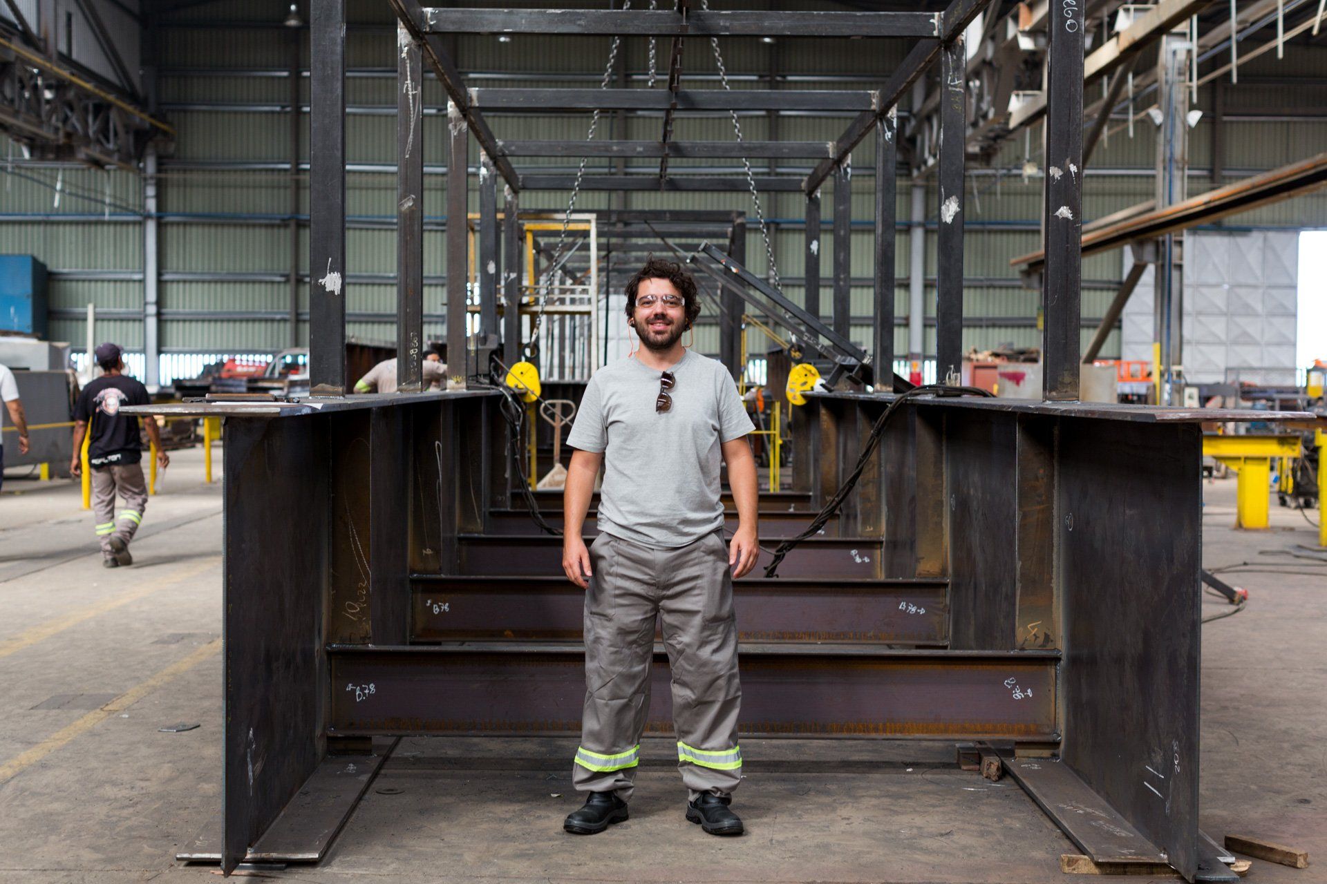 Um homem está diante de uma grande estrutura metálica em uma fábrica.