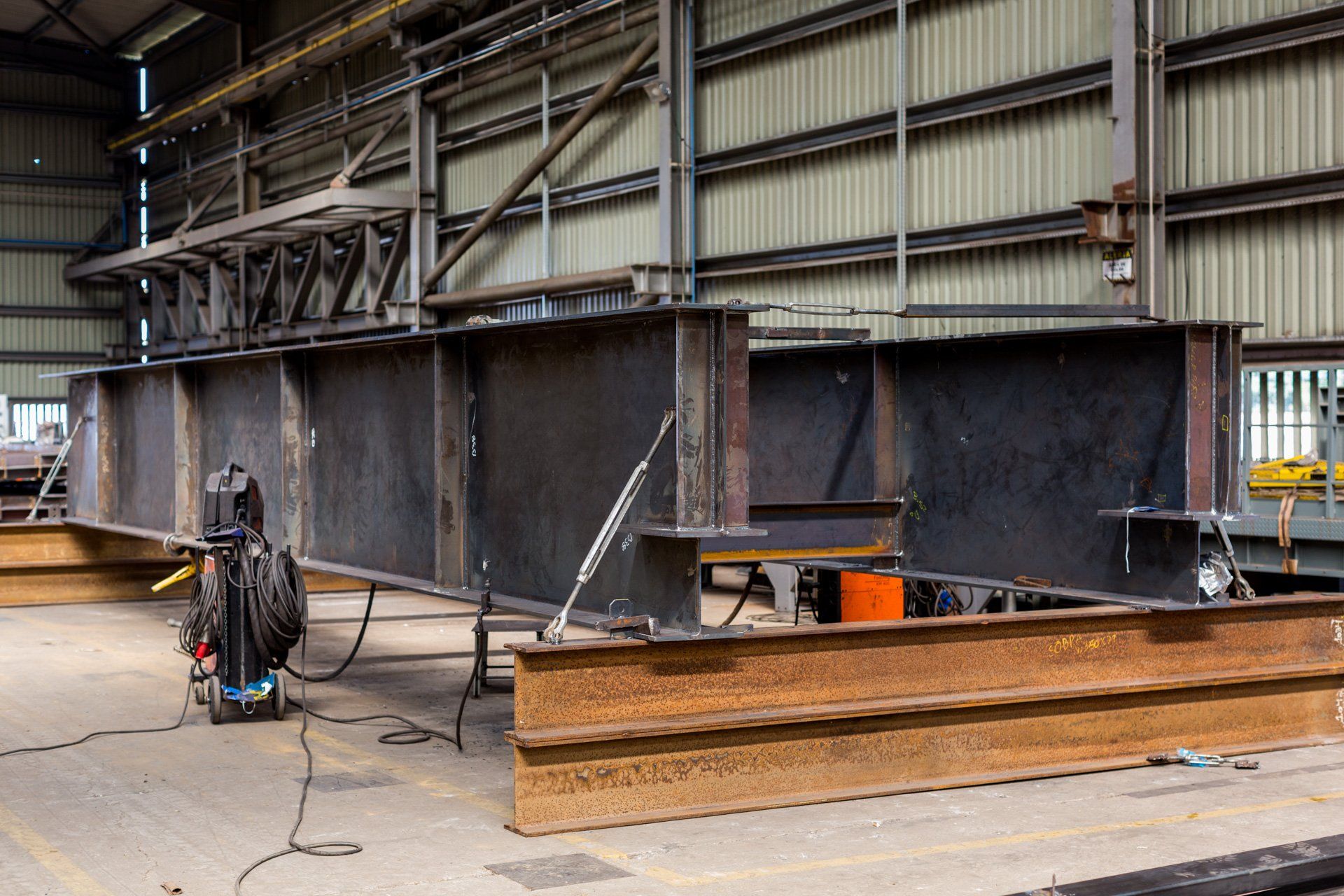 Uma grande estrutura metálica está sendo construída em uma fábrica.