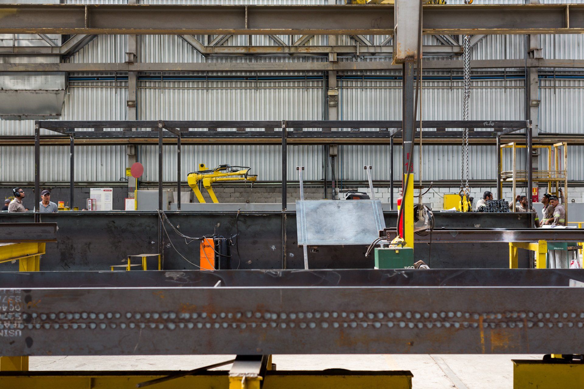 Uma grande estrutura metálica está sendo construída em uma fábrica.