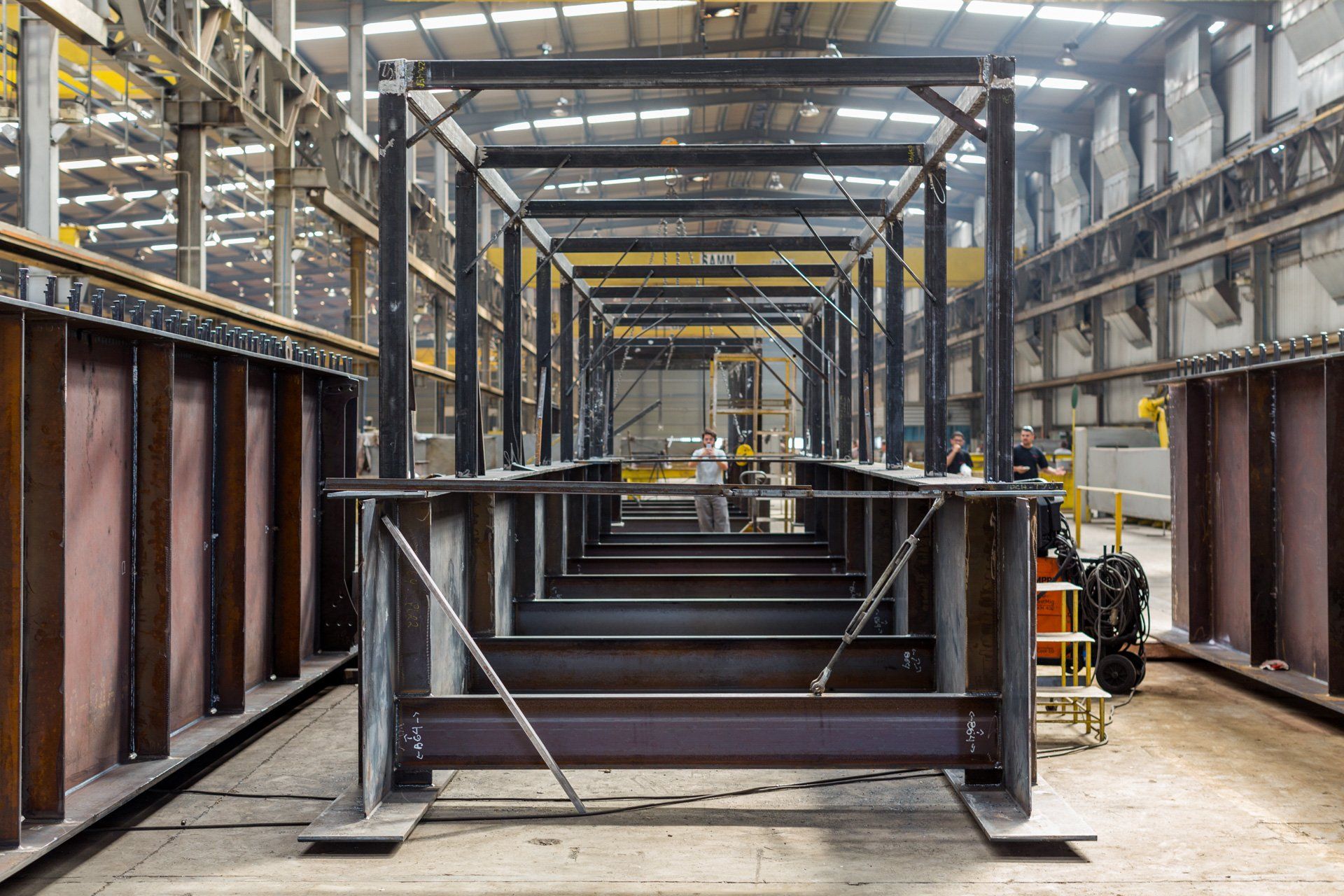 Uma grande estrutura metálica está sendo construída em uma fábrica.