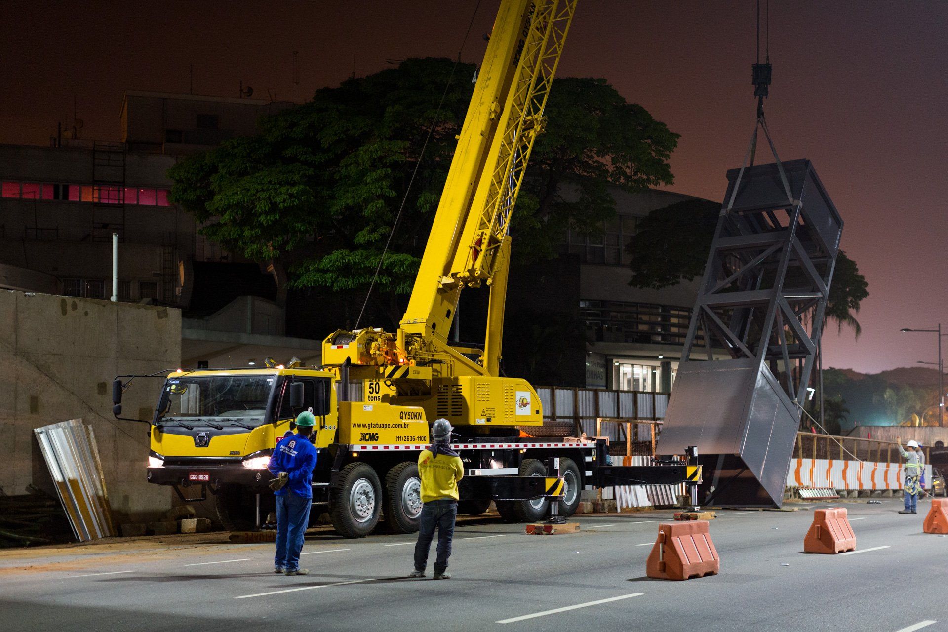 Um guindaste amarelo está sendo usado para levantar um objeto grande